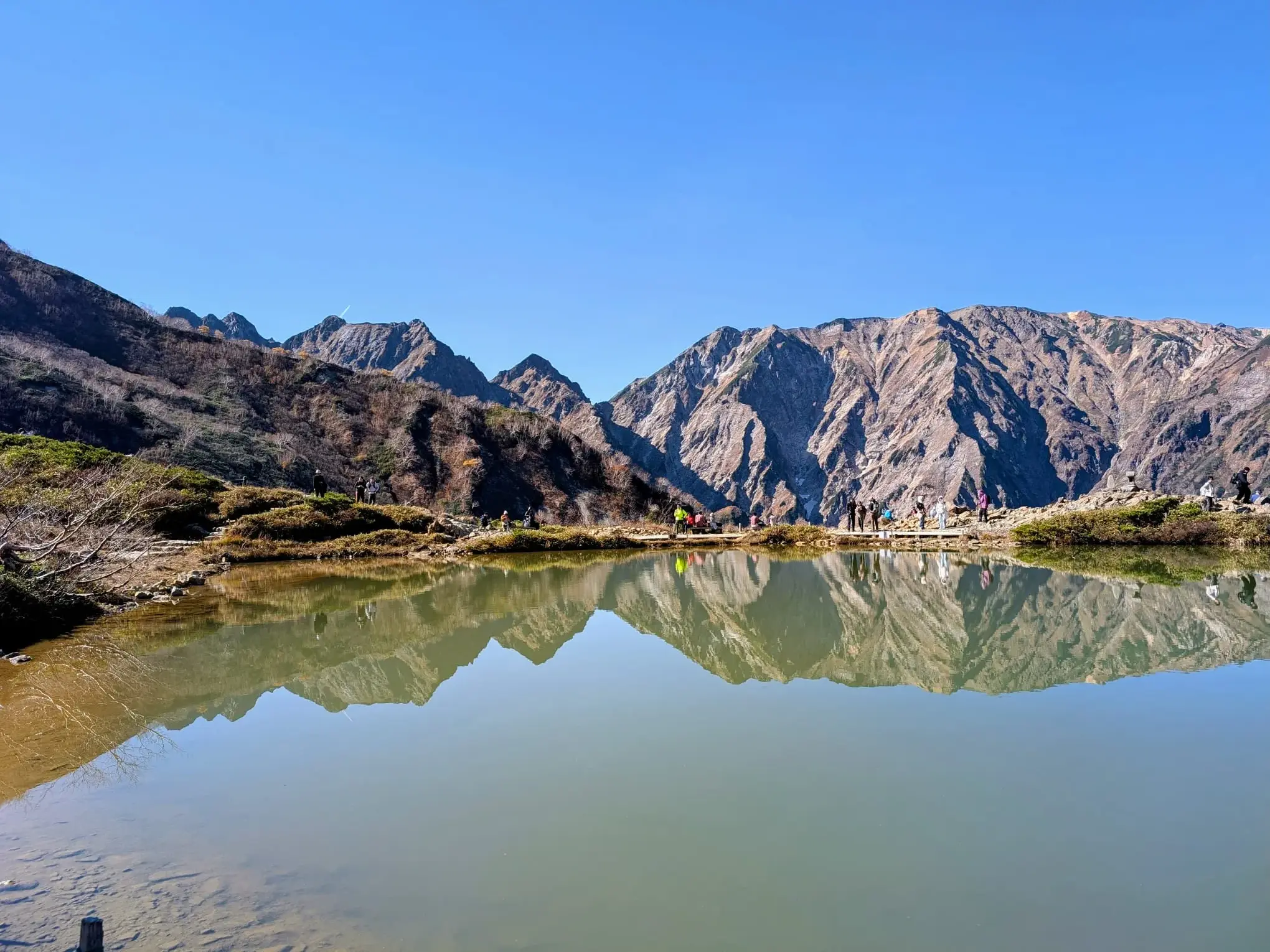 Wanderer am Ufer des Happo-Ike Sees in Hakuba. Die Gipfel der Japanischen Alpen spiegeln sich im klaren Wasser.