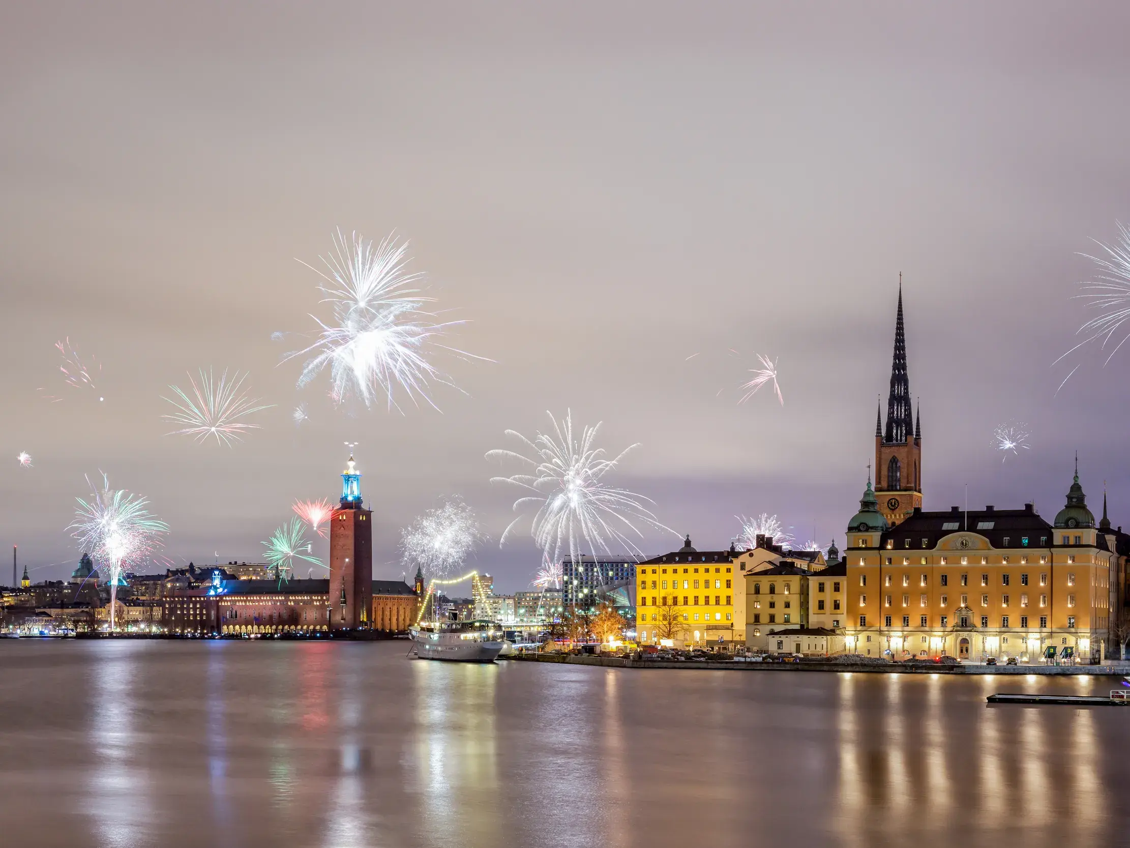 Festliches Silvesterfeuerwerk erleuchtet den Nachthimmel über dem Stadshus und der Altstadt Gamla Stan in Stockholm.