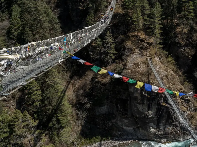 Trekker überqueren die berühmte Hillary-Hängebrücke, geschmückt mit Gebetsfahnen, auf dem Weg nach Namche Bazar in Nepal.