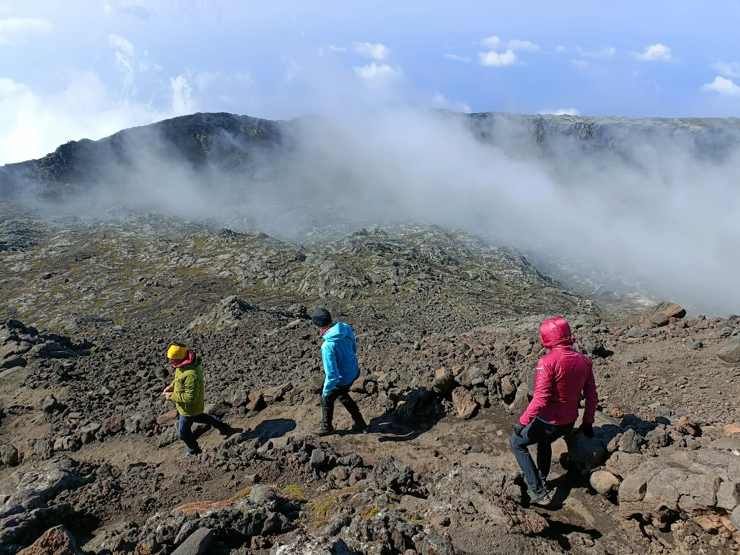 Eine kleine Wandergruppe in bunten Jacken beim anspruchsvollen Trekking durch die Lavafelder des Vulkans Pico auf den Azoren.