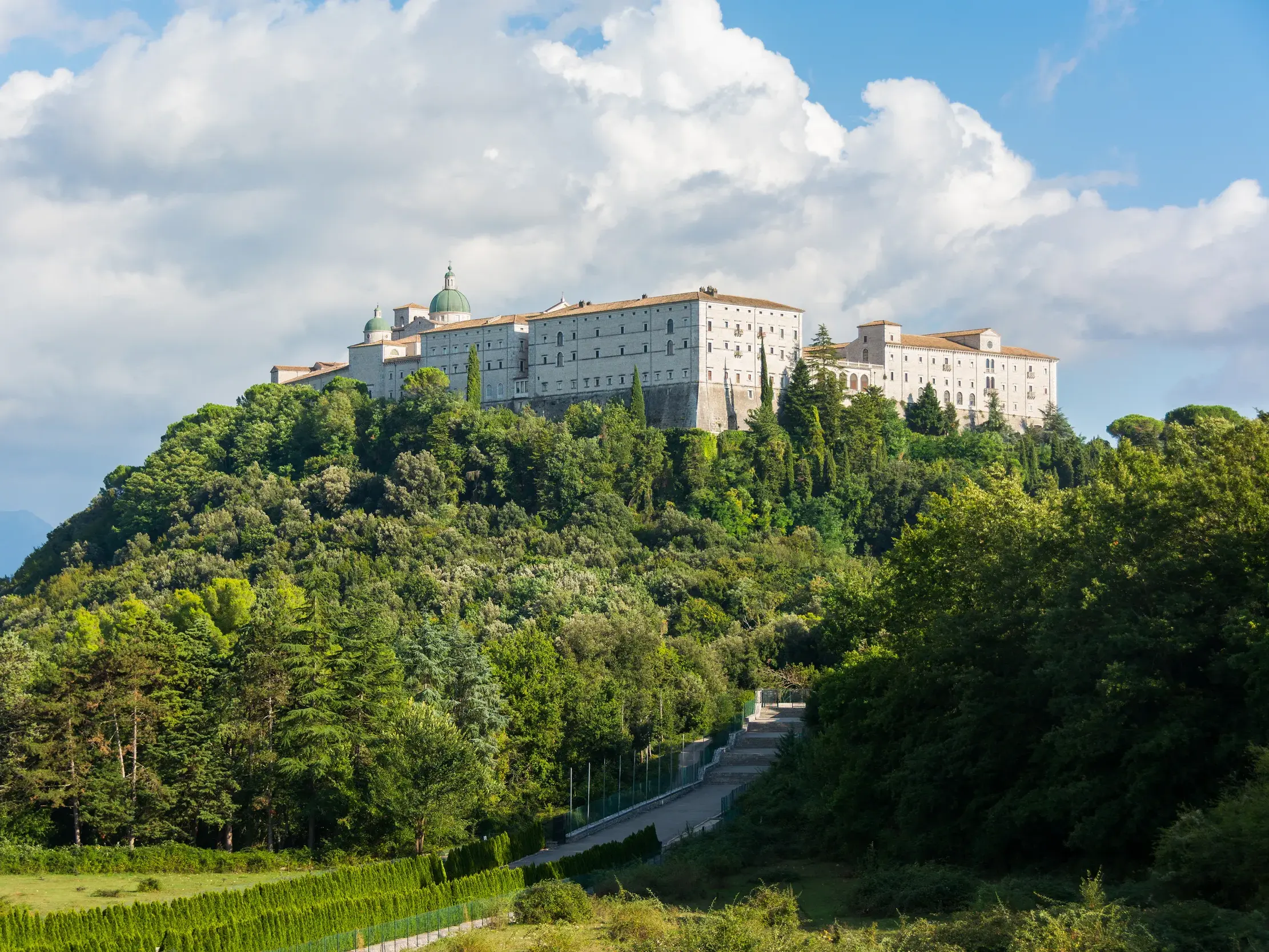 Majestätischer Anblick der Benediktinerabtei Montecassino auf einem bewaldeten Hügel in der weiten Landschaft Mittelitaliens.