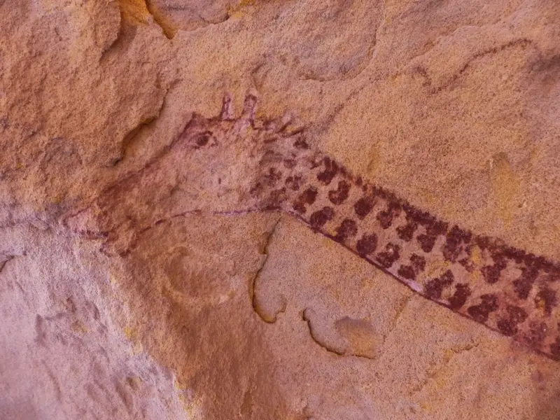 Prähistorische Felsmalerei einer Giraffe auf einer Sandsteinwand im Tassili n'Ajjer Nationalpark in der algerischen Sahara.