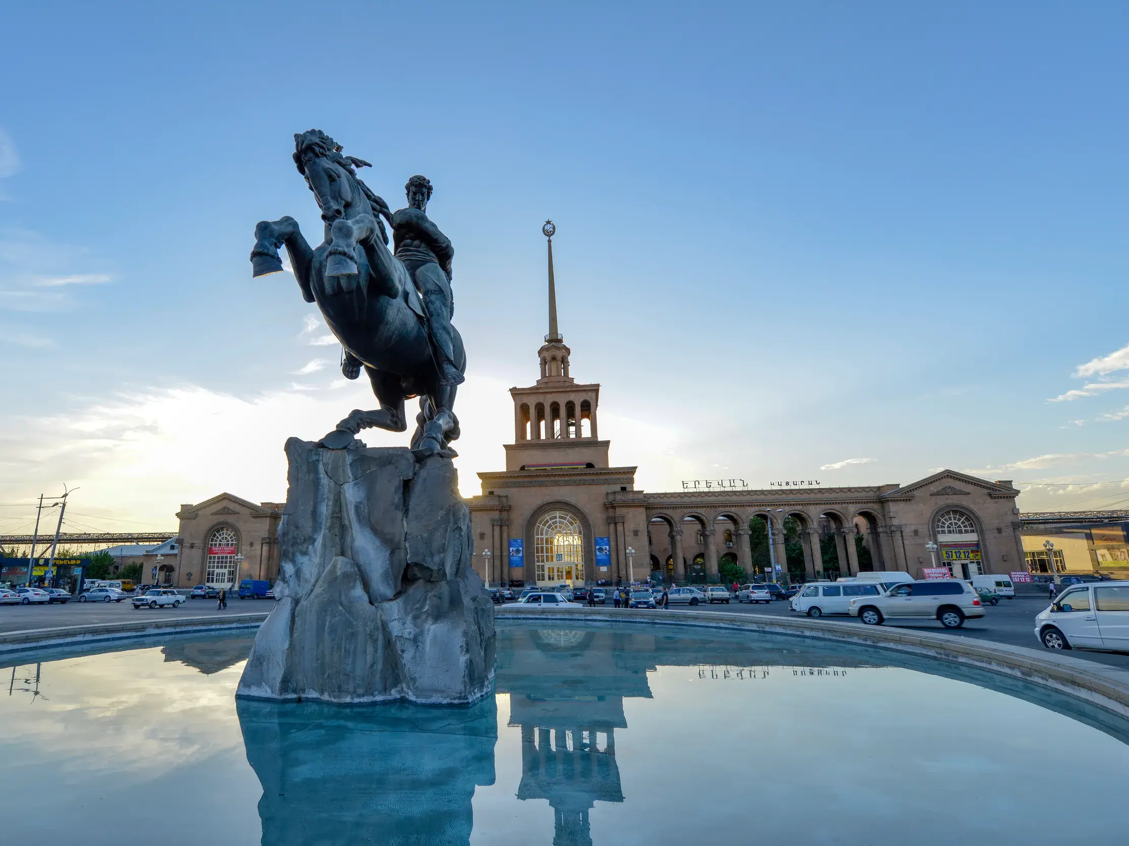 Reiterstatue von Sasuntsi Davit auf dem Bahnhofsplatz in Eriwan, die sich im Brunnen vor dem Gebäude spiegelt.