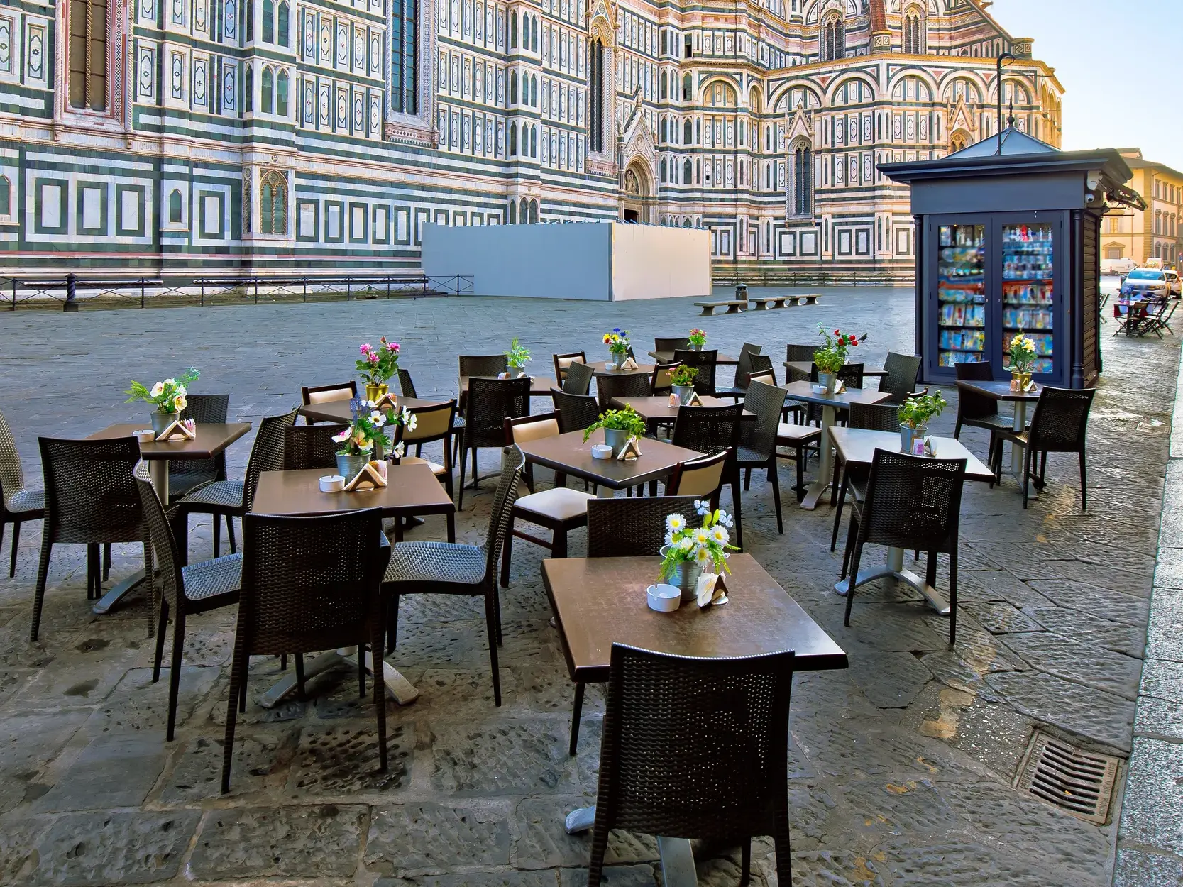 Straßencafé mit gedeckten Tischen auf der Piazza del Duomo vor der berühmten Fassade des Doms von Florenz am Morgen.