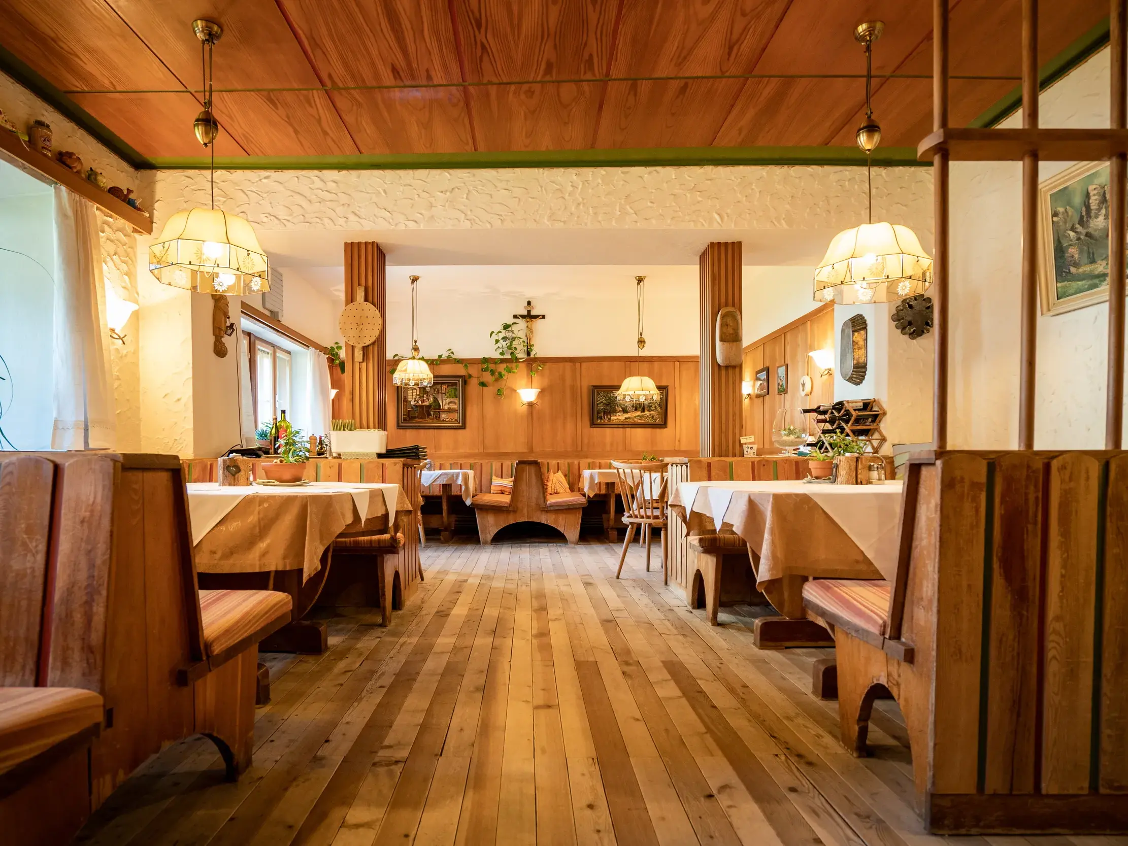 Rustikale Gaststube im Gasthof Raiffeisen in Innervillgraten mit Holzbänken, gedeckten Tischen und warmem Ambiente in Osttirol.