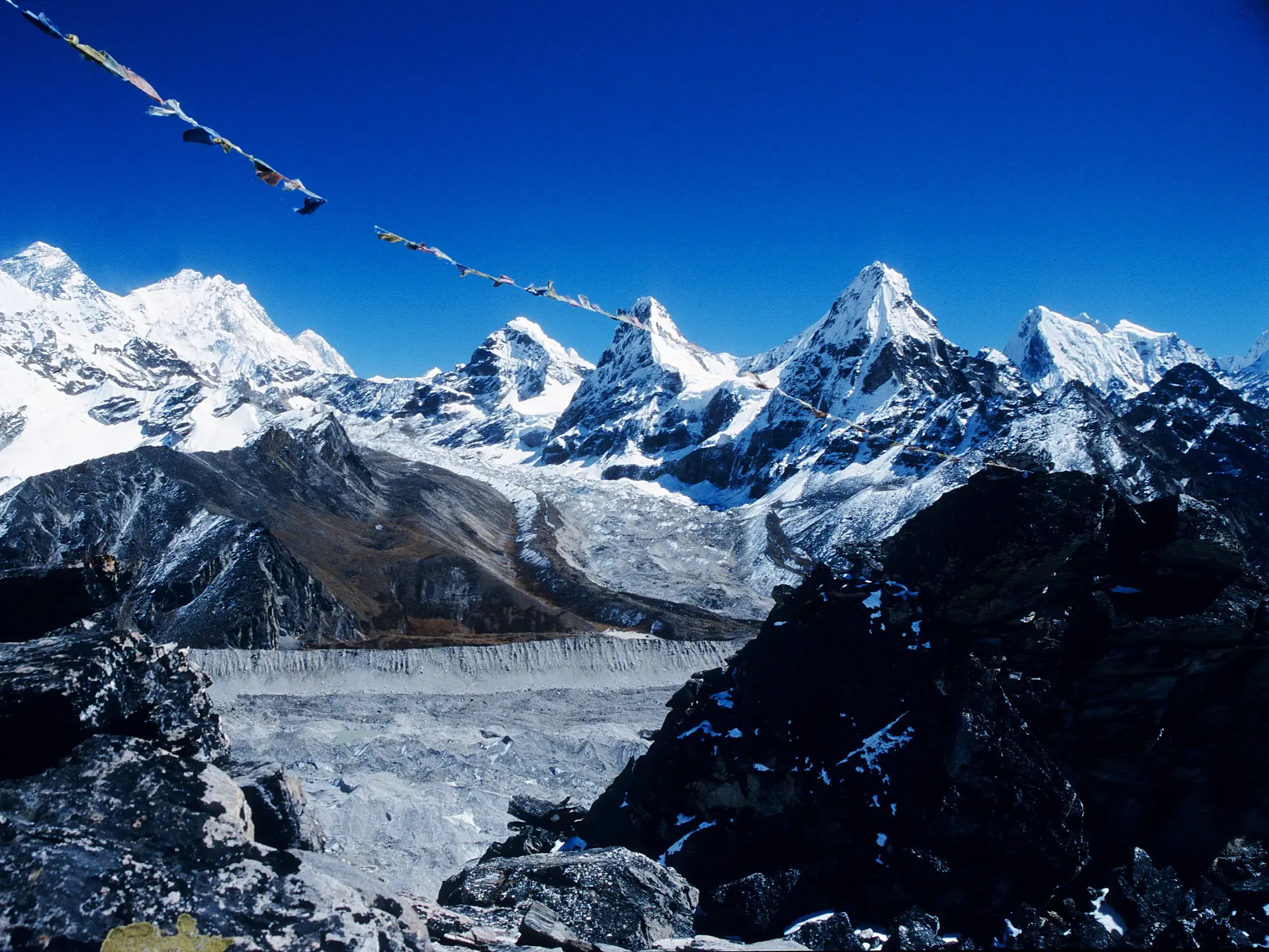 Gebetsfahnen am Renjo La Pass mit Blick auf den Ngozumpa-Gletscher und die Achttausender Mount Everest und Lhotse in Nepal.