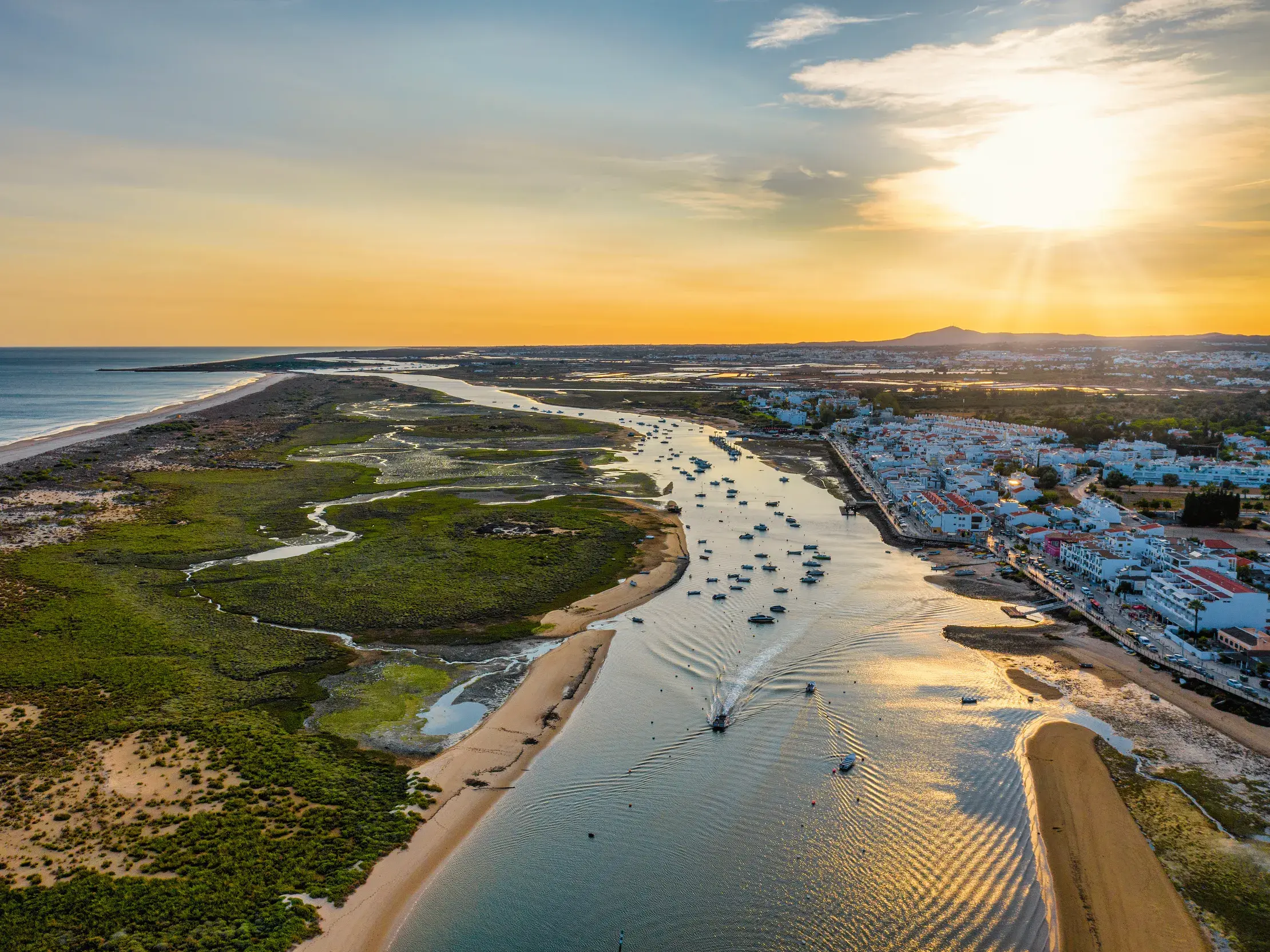 Luftaufnahme der Lagunenlandschaft im Naturschutzgebiet Ria Formosa mit Booten an der Algarve im Abendlicht