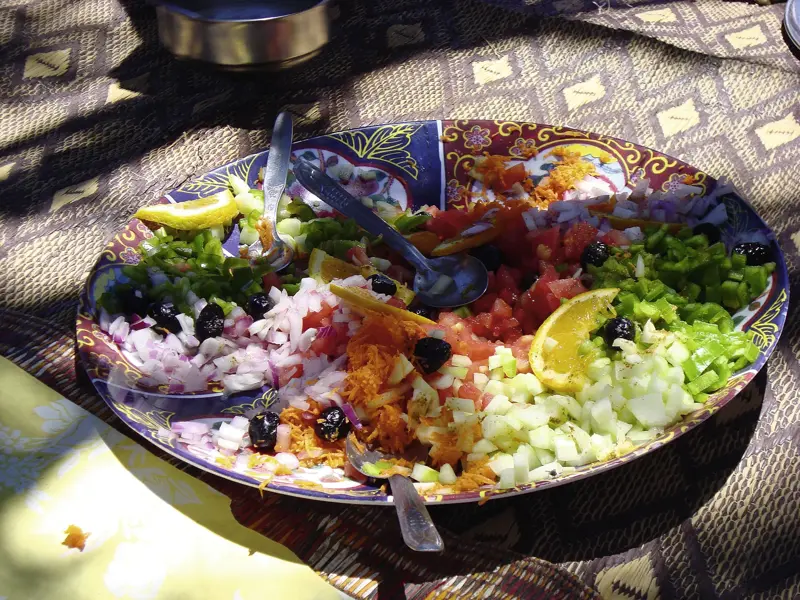 Farbenfroher, marokkanischer Salat auf einer verzierten Platte als stärkendes Mittagessen während des Kamel-Trekkings.