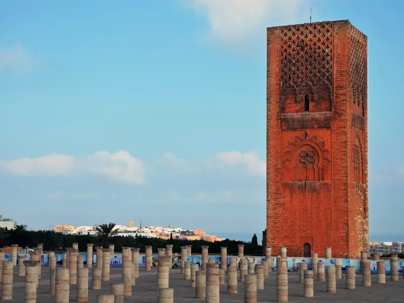 Der unvollendete Hassan-Turm in der Königsstadt Rabat ragt über den Steinsäulen der alten Moschee in den blauen Himmel.