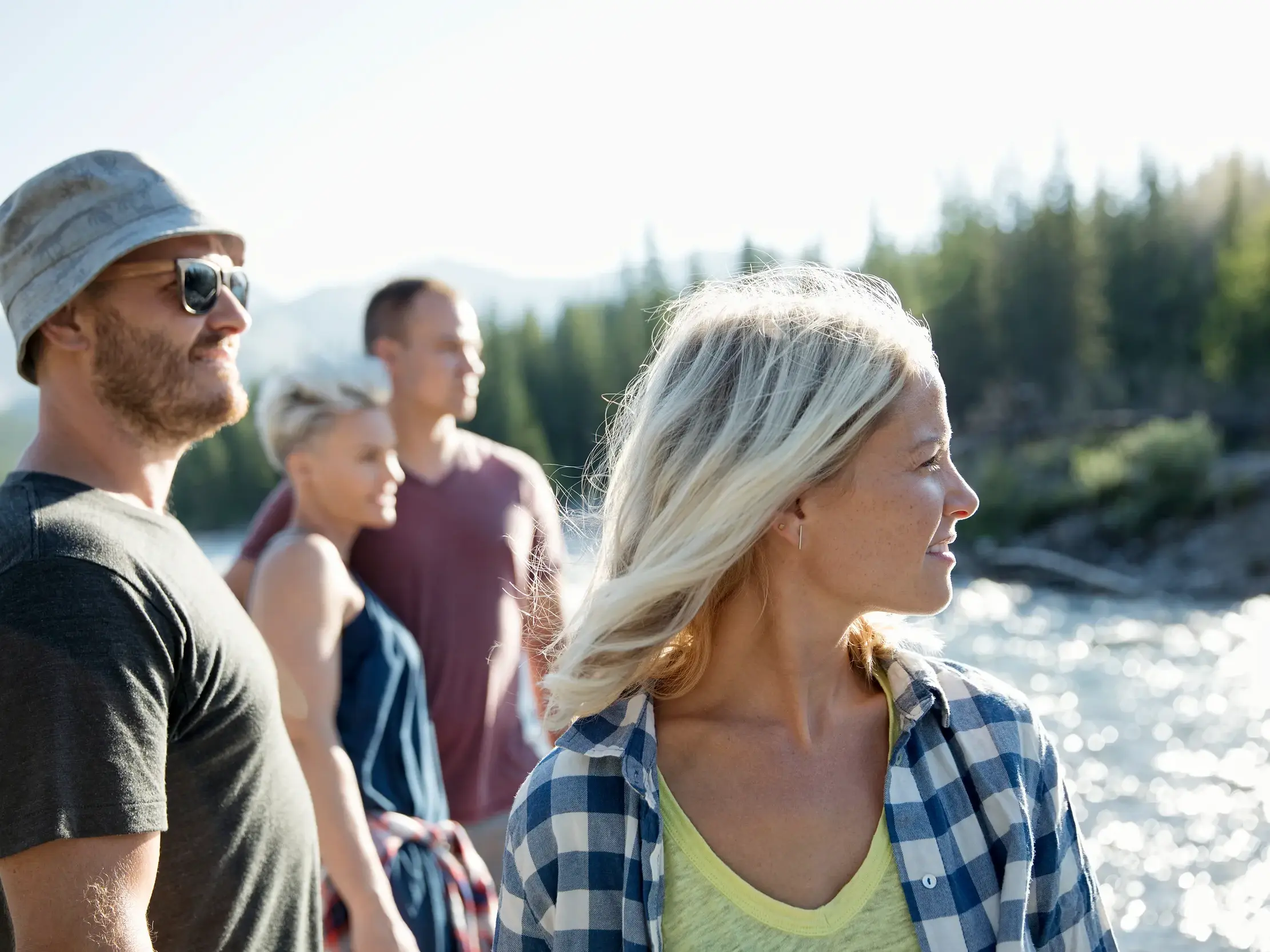 Vier junge Reisende stehen am sonnigen Ufer eines Flusses in Norwegen.