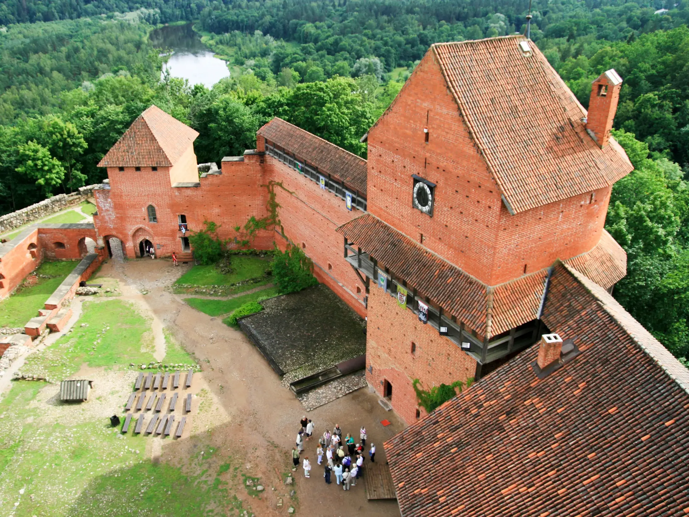 Aussicht von oben auf die Burgruine Turaida im Gauja Nationalpark, wo eine Reisegruppe den historischen Innenhof erkundet.