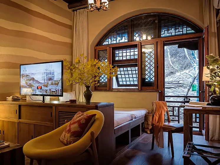 Rustikales Pensionszimmer bei Simatai mit gestreifter Lehmwand, Holzmöbeln und großem, offenem Fenster mit Blick zur Natur.