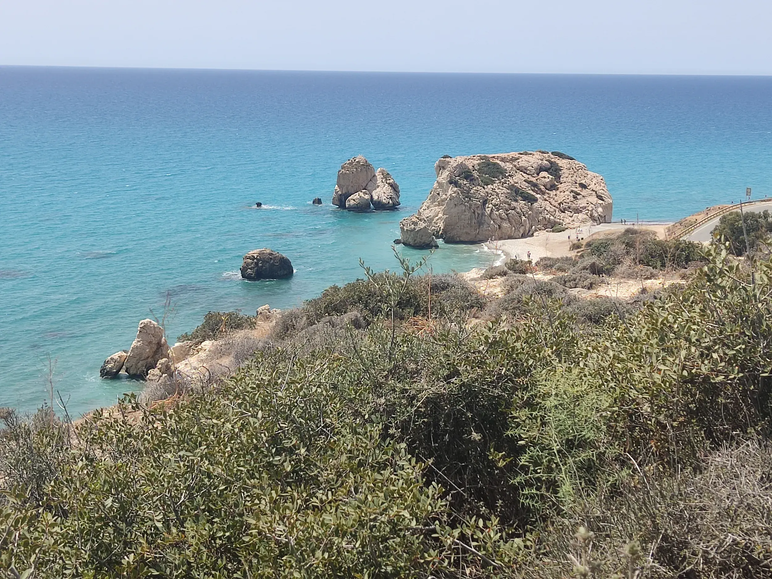 Blick von einer Wanderung auf den Felsen der Aphrodite, Petra tou Romiou, und das türkisfarbene Meer an der Küste Zyperns.