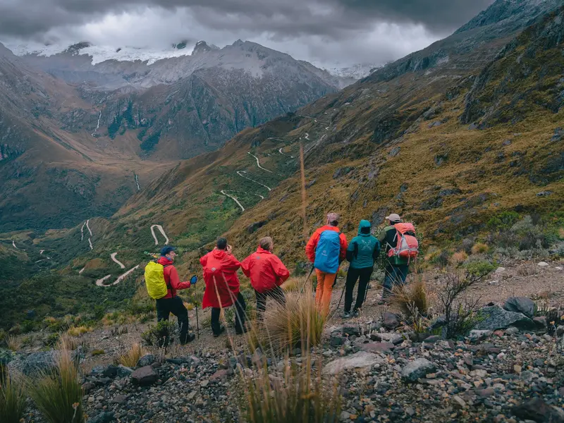 Eine Hauser-Wandergruppe blickt beim Trekking in der Cordillera Blanca auf ein weites Tal mit einer Serpentinenstraße.