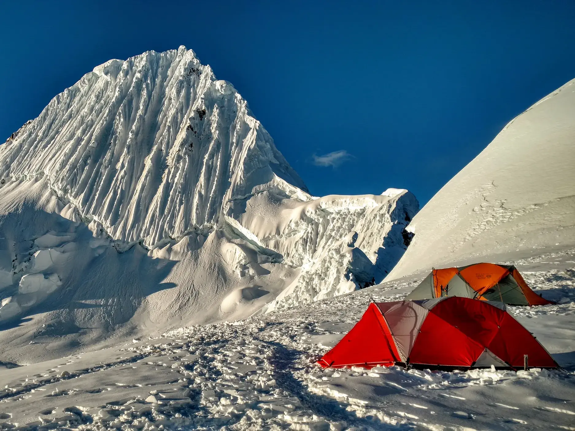 Zwei Zelte im Alpamayo-Hochlager in der Cordillera Blanca mit Blick auf den schneebedeckten Gipfel des Alpamayo.
