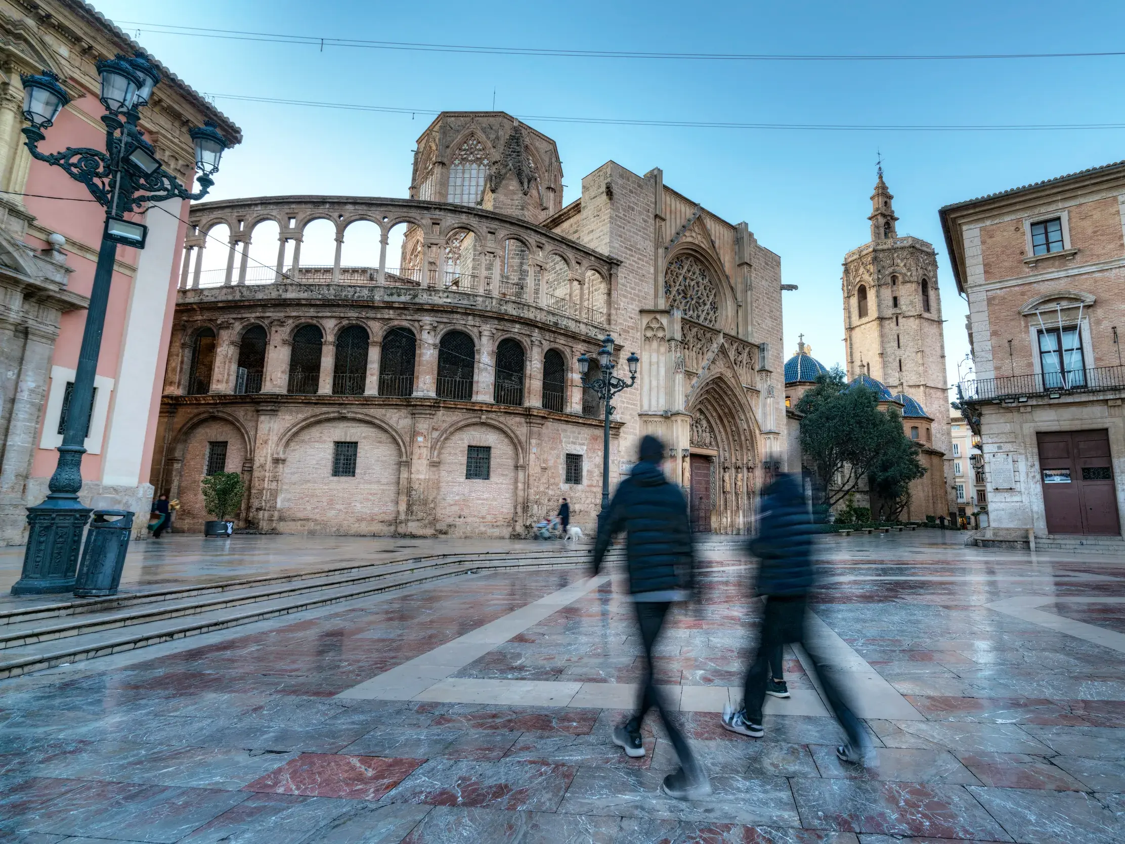 Morgenstimmung in der Altstadt von Valencia: Passanten in Bewegungsunschärfe überqueren den Platz vor der imposanten Kathedrale.