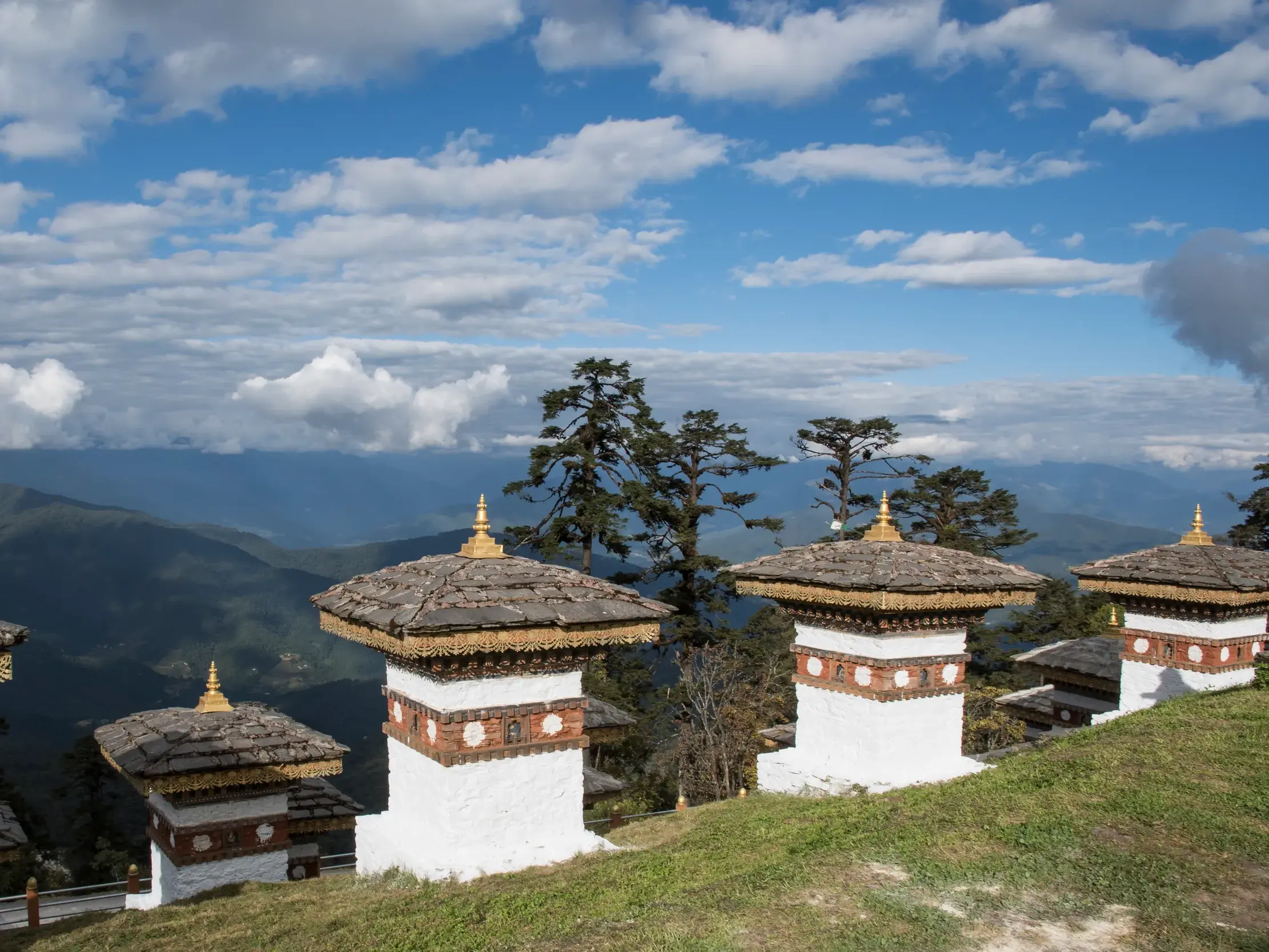 Eine Reihe der 108 Druk Wangyal Chörten am Dochu-La Pass in Bhutan mit Blick auf das majestätische Himalaya-Panorama.