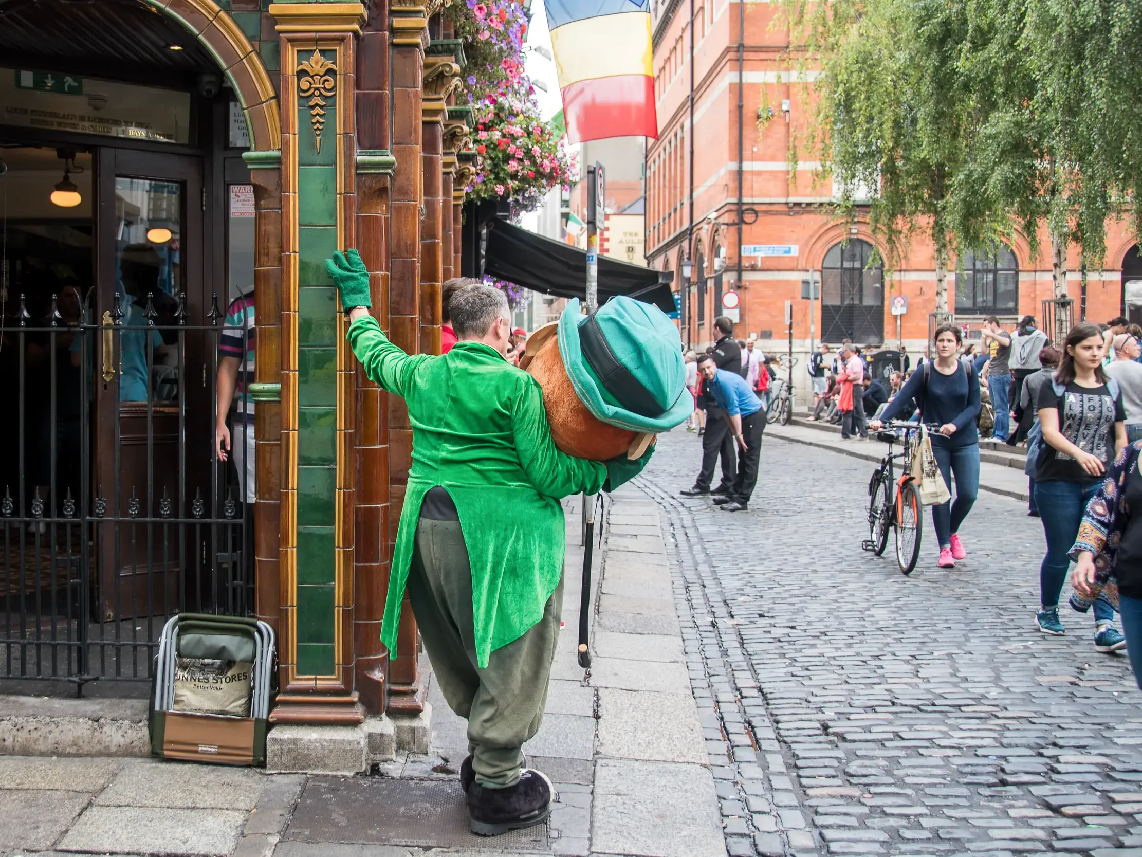 Als Leprechaun verkleideter Straßenkünstler auf einer belebten Kopfsteinpflasterstraße im Zentrum von Dublin, Irland.
