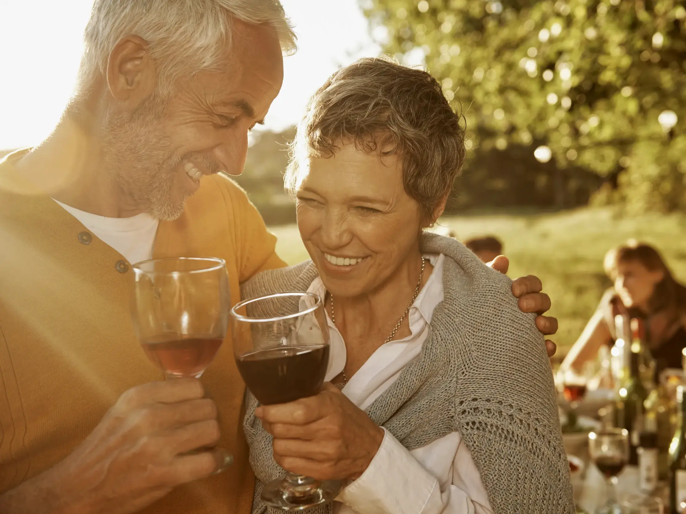 Glückliches Paar bei einer Weinprobe in Istrien, umgeben von warmem Sonnenlicht und anderen Gästen einer Kleingruppenreise.