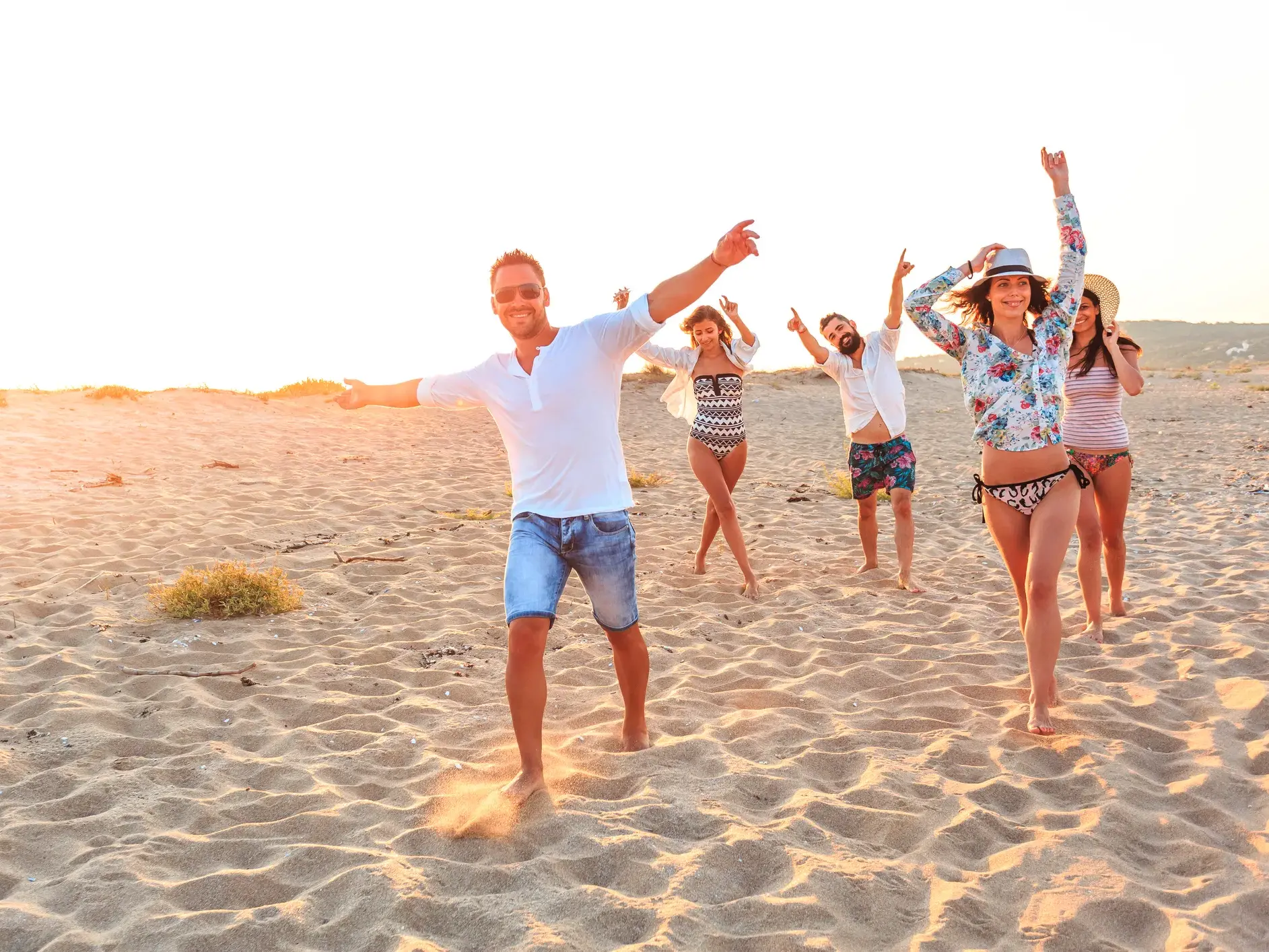 Eine Gruppe junger Leute feiert ausgelassen am Strand bei Sonnenuntergang während einer Gruppenreise für junge Leute in Indonesien.