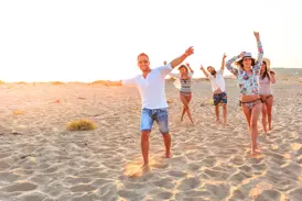 Eine Gruppe junger Leute feiert ausgelassen am Strand bei Sonnenuntergang während einer Gruppenreise für junge Leute in Indonesien.