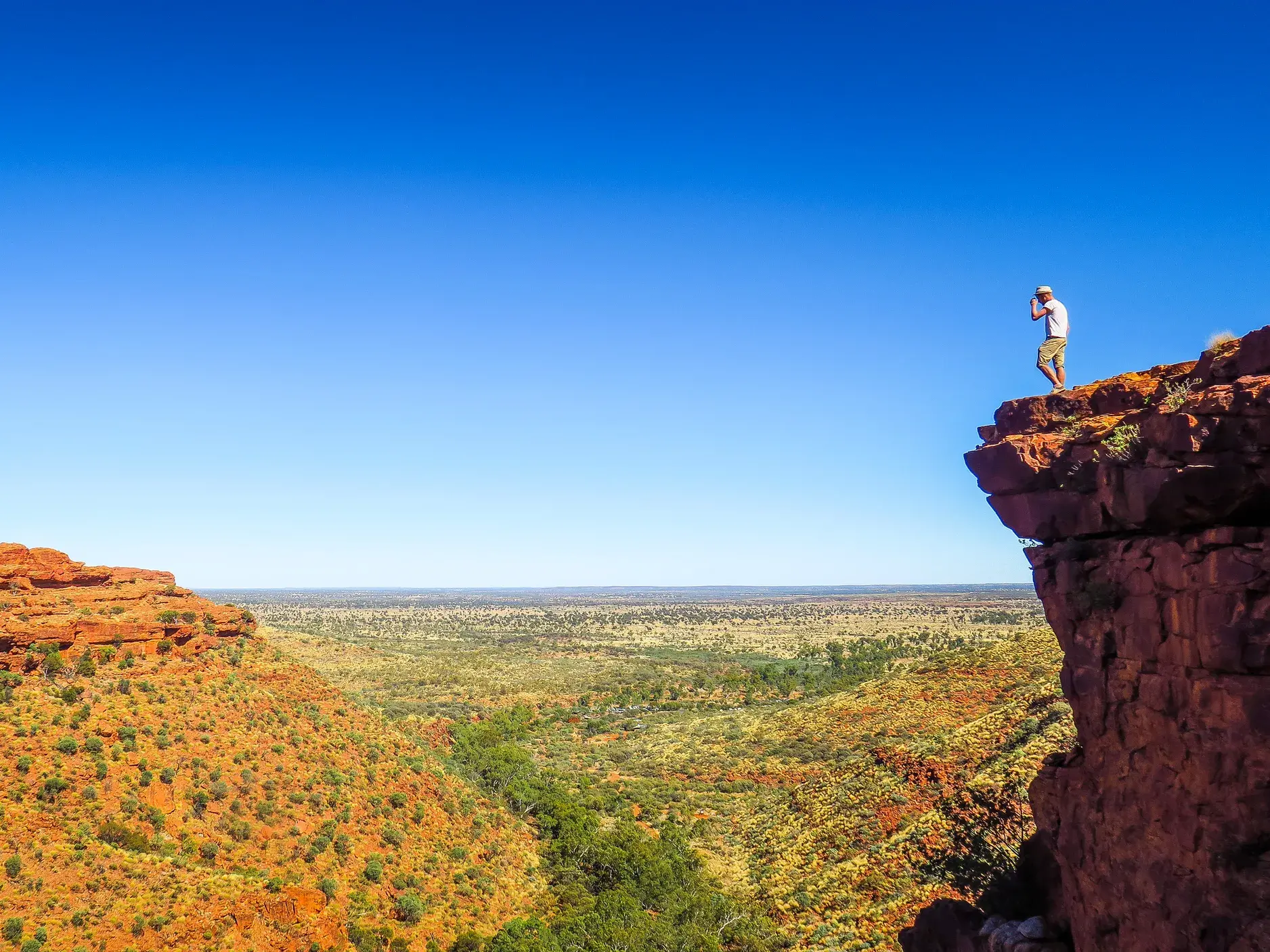 Ein Wanderer steht auf einer Felsklippe und genießt den weiten Ausblick über den rostroten Kings Canyon in Australien.