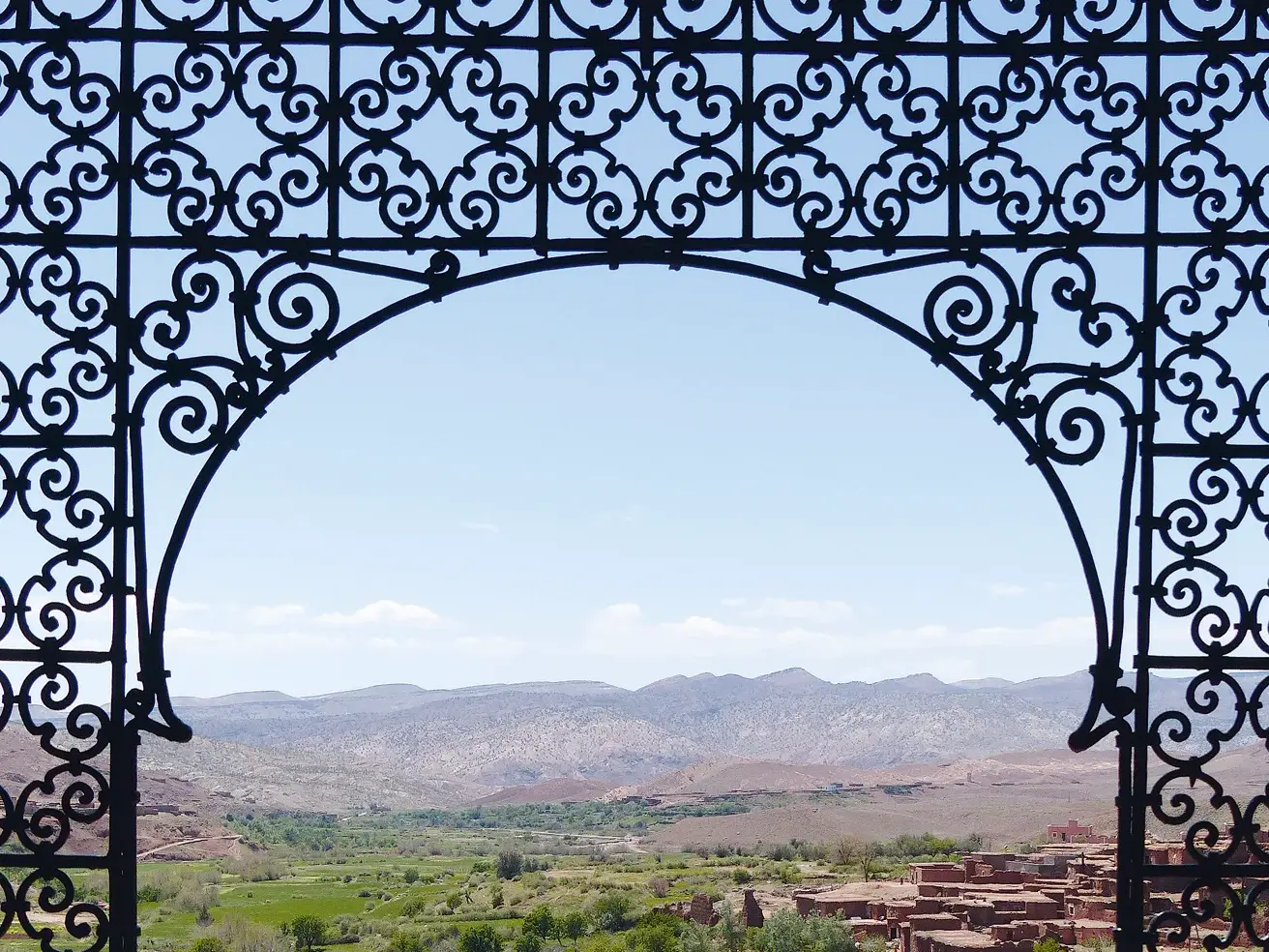 Kunstvolles Bogentor der Kasbah Telouet rahmt den Ausblick auf die weite Berglandschaft des Hohen Atlas in Marokko.