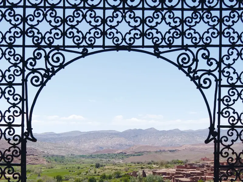 Kunstvolles Bogentor der Kasbah Telouet rahmt den Ausblick auf die weite Berglandschaft des Hohen Atlas in Marokko.