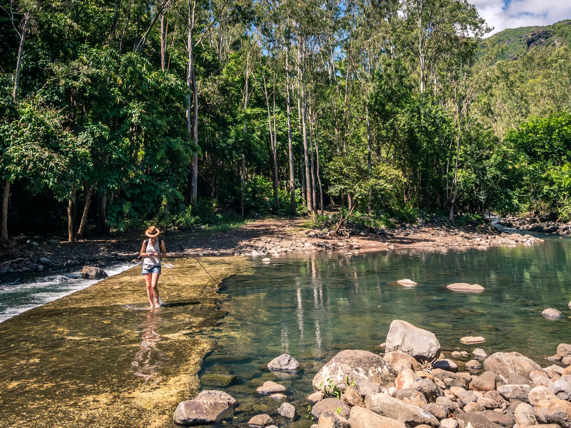 Junge Alleinreisende mit Hut erkundet die tropische Flusslandschaft im Black-River-Gorges-Nationalpark auf Mauritius.