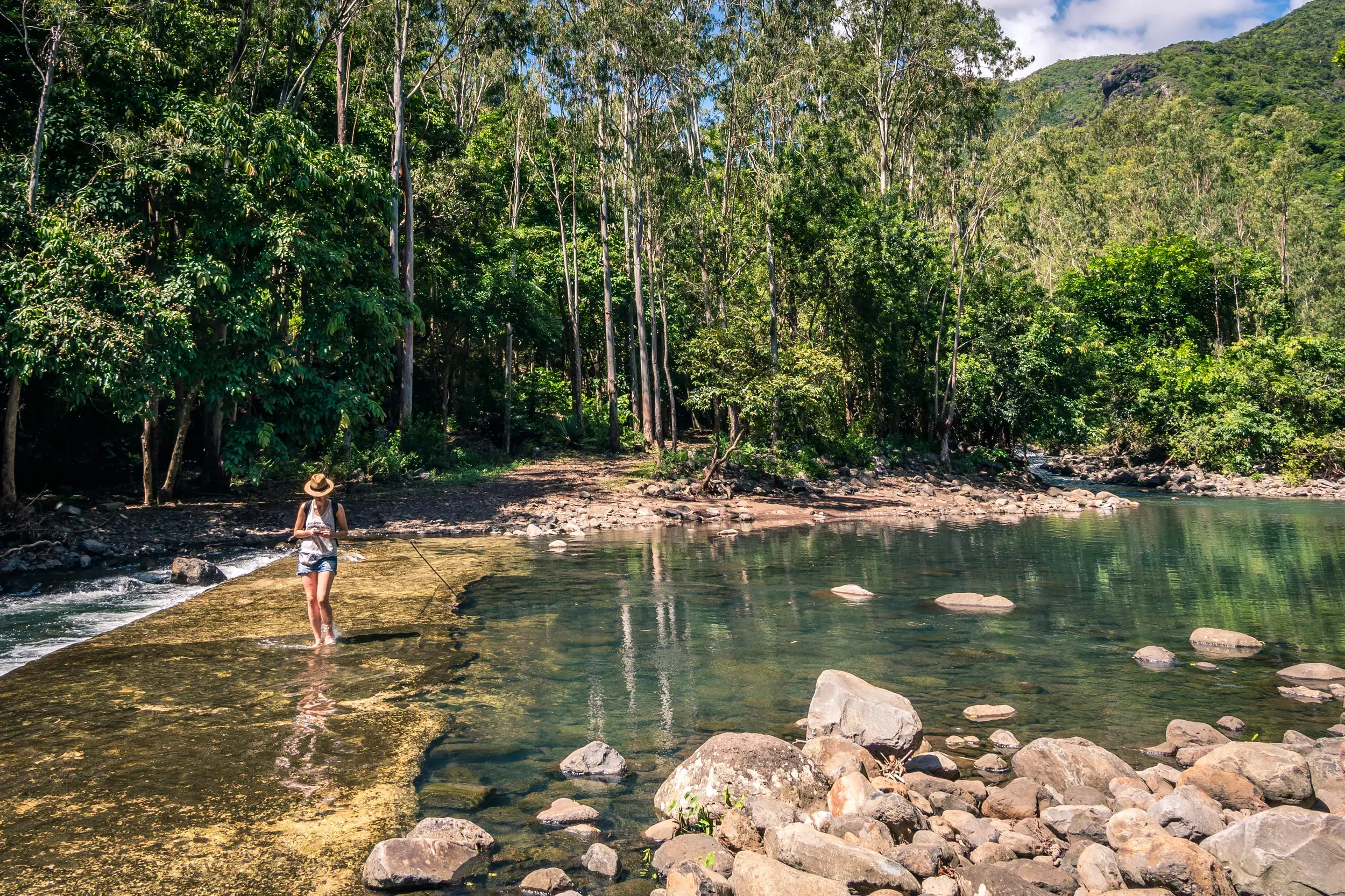 Junge Alleinreisende mit Hut erkundet die tropische Flusslandschaft im Black-River-Gorges-Nationalpark auf Mauritius.