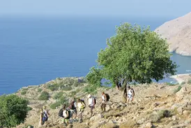 Eine Hauser Exkursionen Wandergruppe auf einem felsigen Küstenpfad mit weitem Blick über den blauen Saronischen Golf in Griechenland.