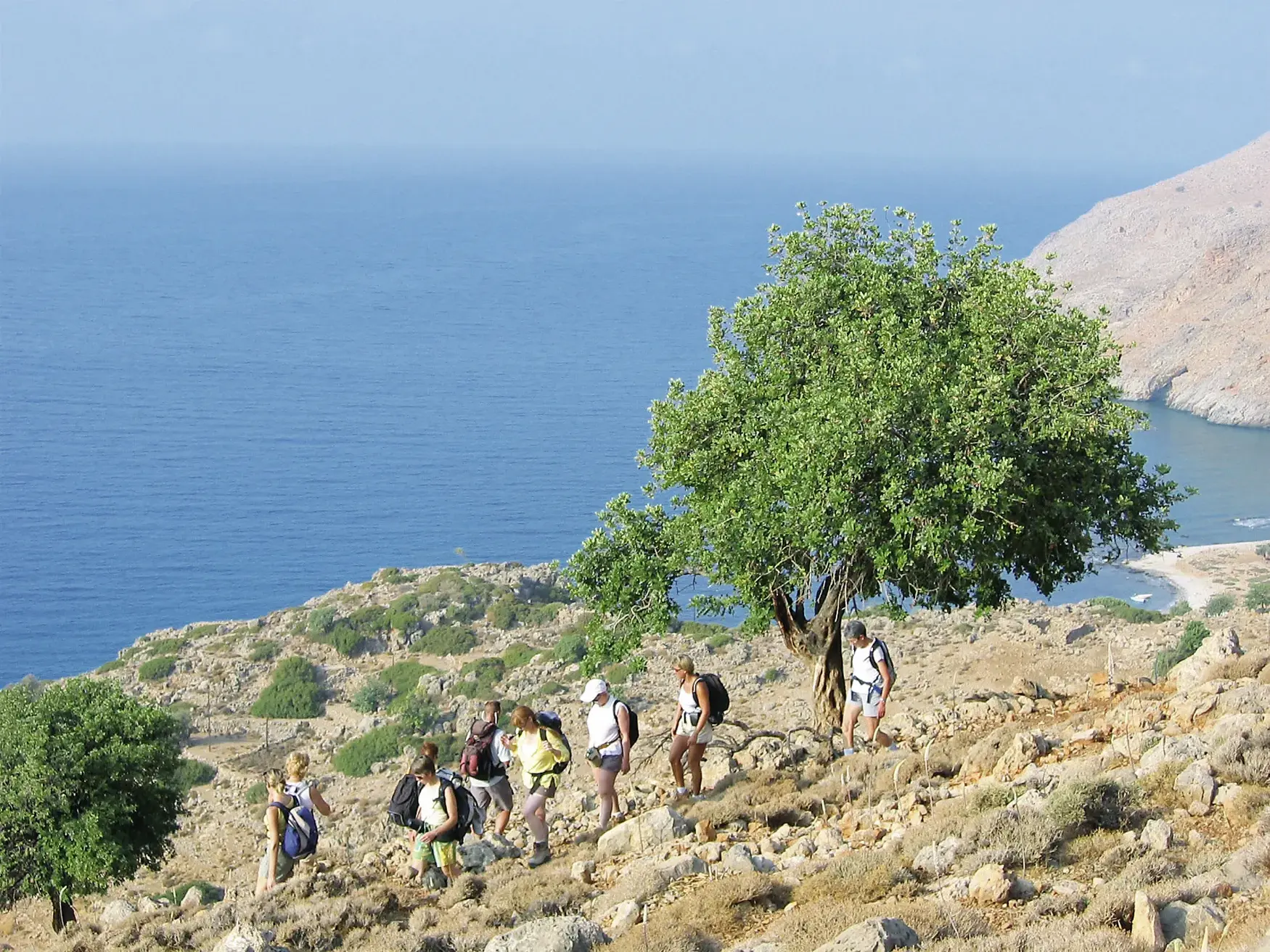 Eine Reisegruppe wandert auf dem Fernwanderweg E4 entlang der Südküste Kretas mit Panoramablick auf das tiefblaue Meer.
