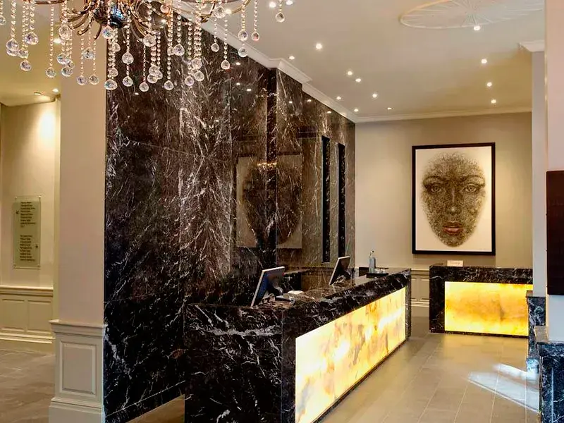 Eleganter Empfangsbereich des Hotel Radisson Blu London Euston Square mit beleuchtetem Marmortresen und moderner Kunst.