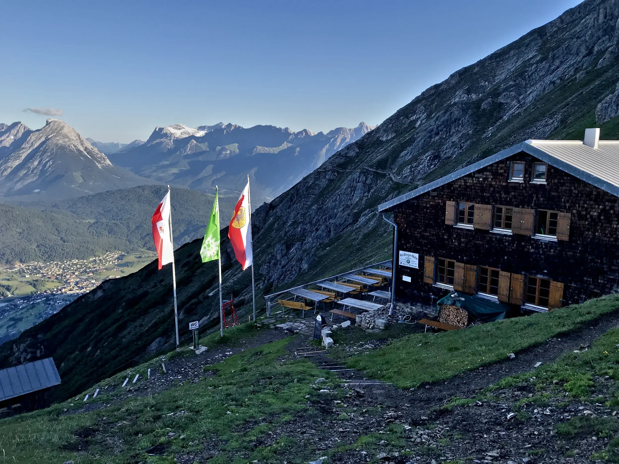 Die Nördlinger Hütte an einem sonnigen Tag am Berghang mit Panoramablick auf das Karwendelgebirge in Tirol.