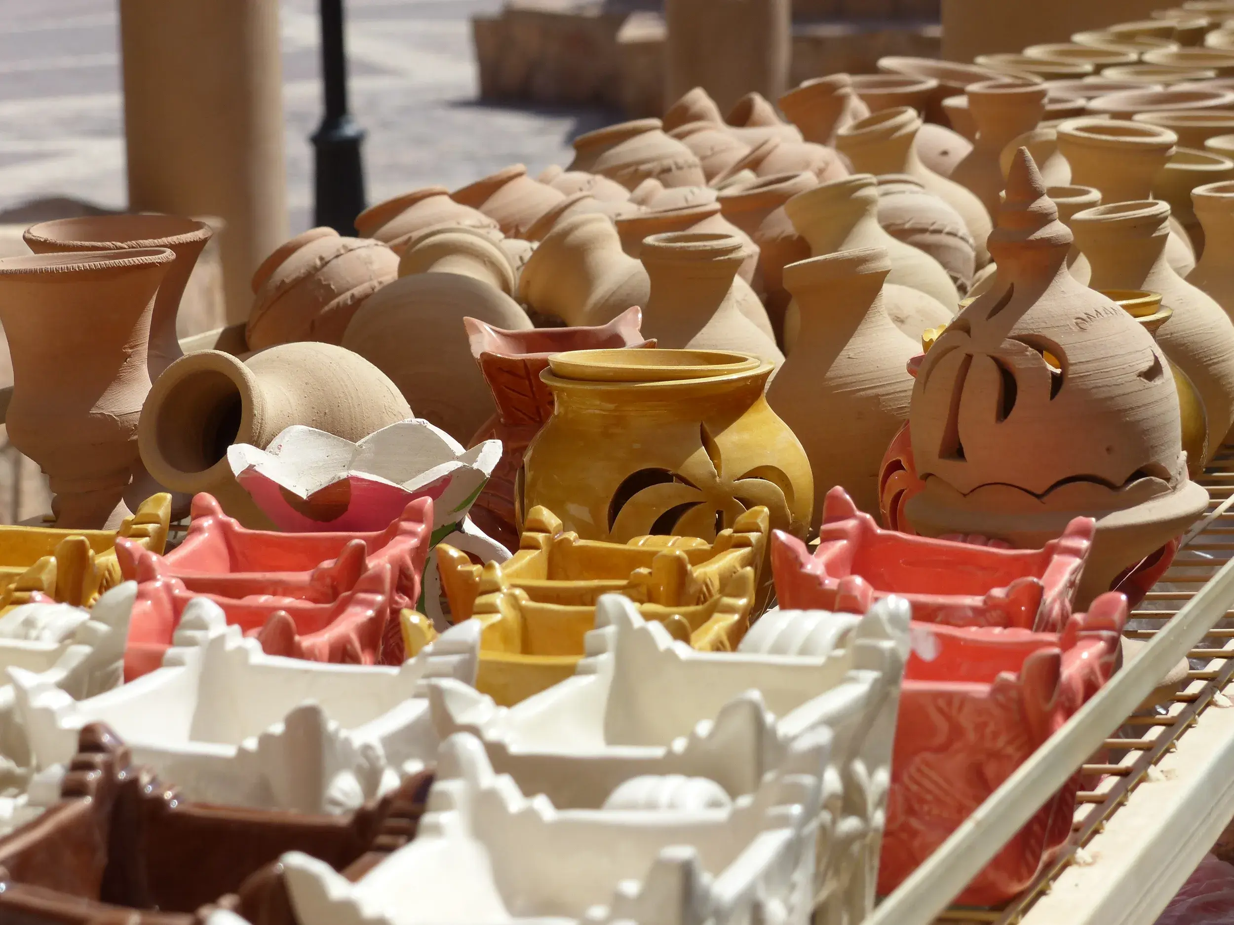 Bunte, handgefertigte Töpferwaren und Keramik auf einem Verkaufsstand im Souq von Nizwa im Oman ausgestellt.