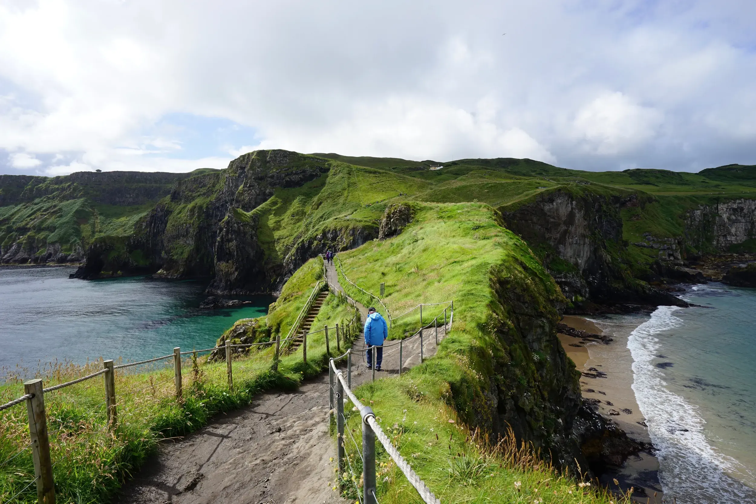 Wanderer auf dem Küstenpfad des Causeway Coast Way entlang der grünen Klippen und des Atlantiks in Nordirland.