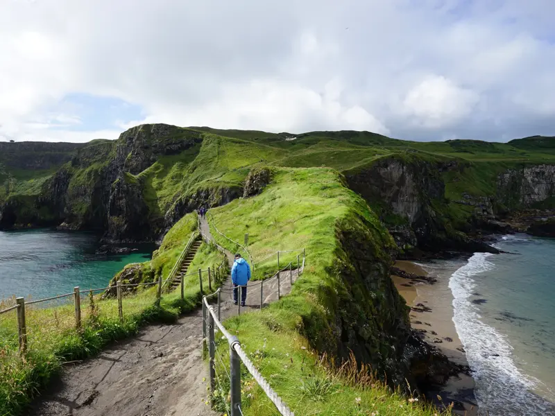 Wanderer auf dem Küstenpfad des Causeway Coast Way entlang der grünen Klippen und des Atlantiks in Nordirland.