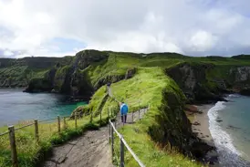 Wanderer auf dem Küstenpfad des Causeway Coast Way entlang der grünen Klippen und des Atlantiks in Nordirland.