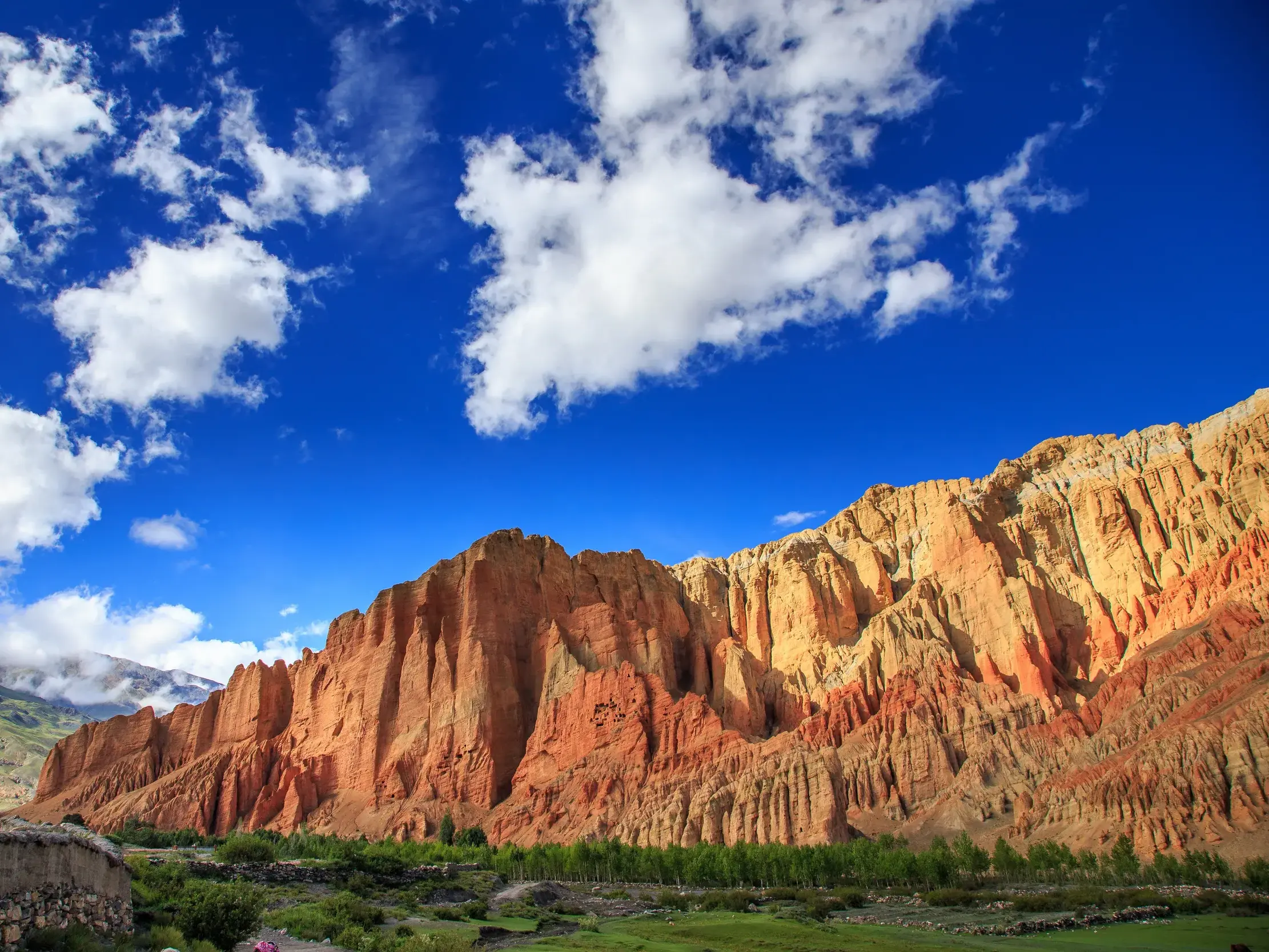 Spektakuläre rote Felsformationen bei Dhakmar auf einer Trekkingreise durch das Mustang-Tal in Nepal unter blauem Himmel.