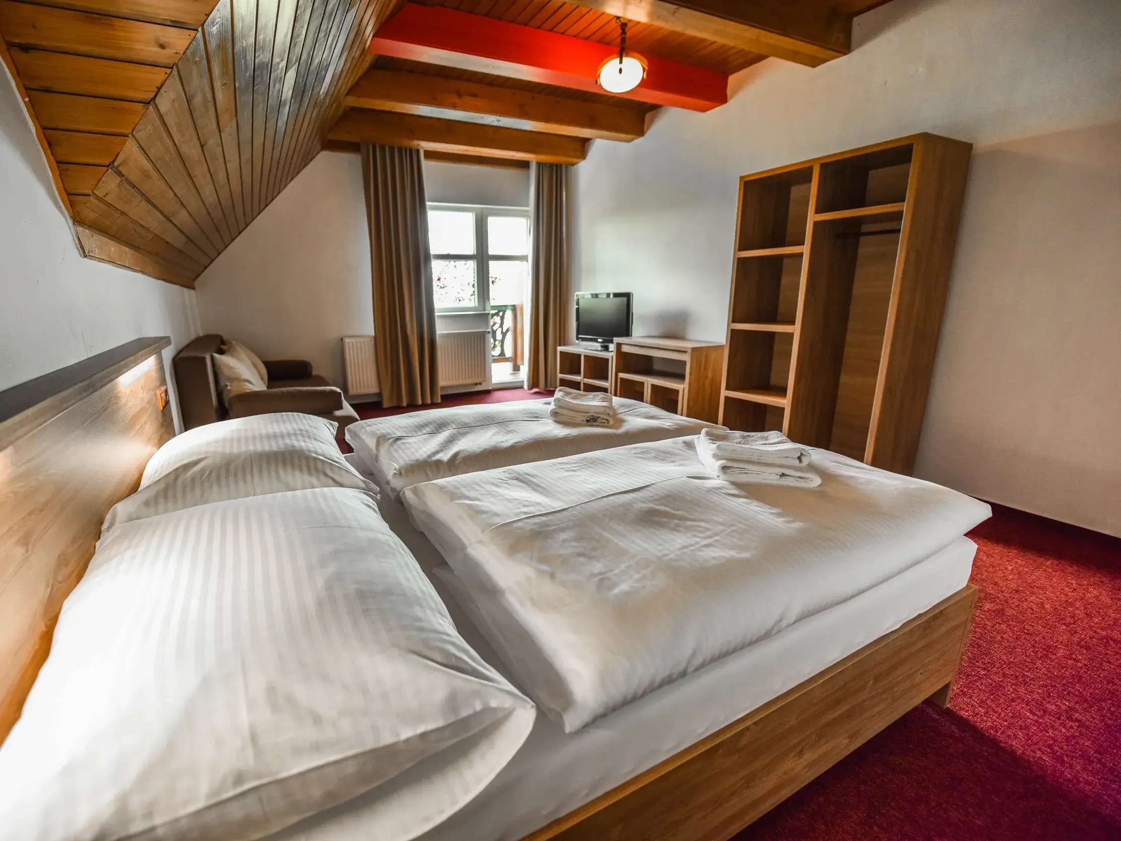 Innenansicht eines rustikalen Doppelzimmers mit Holzdecke in der Pension Lomnicky in Stará Lesná in der Hohen Tatra.