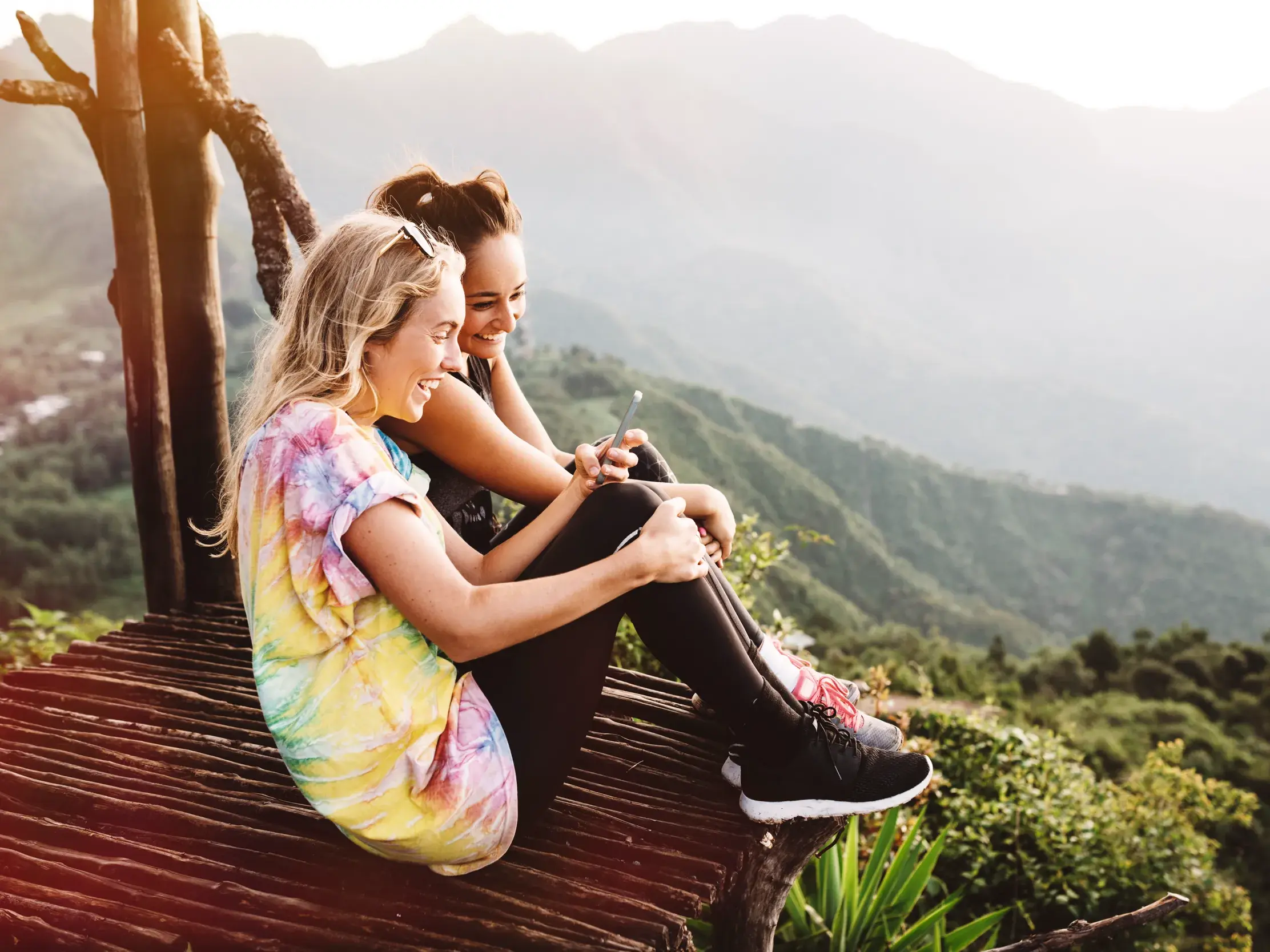 Zwei junge Frauen einer Gruppenreise genießen lachend den Ausblick auf die Berglandschaft am Atitlánsee in Guatemala.