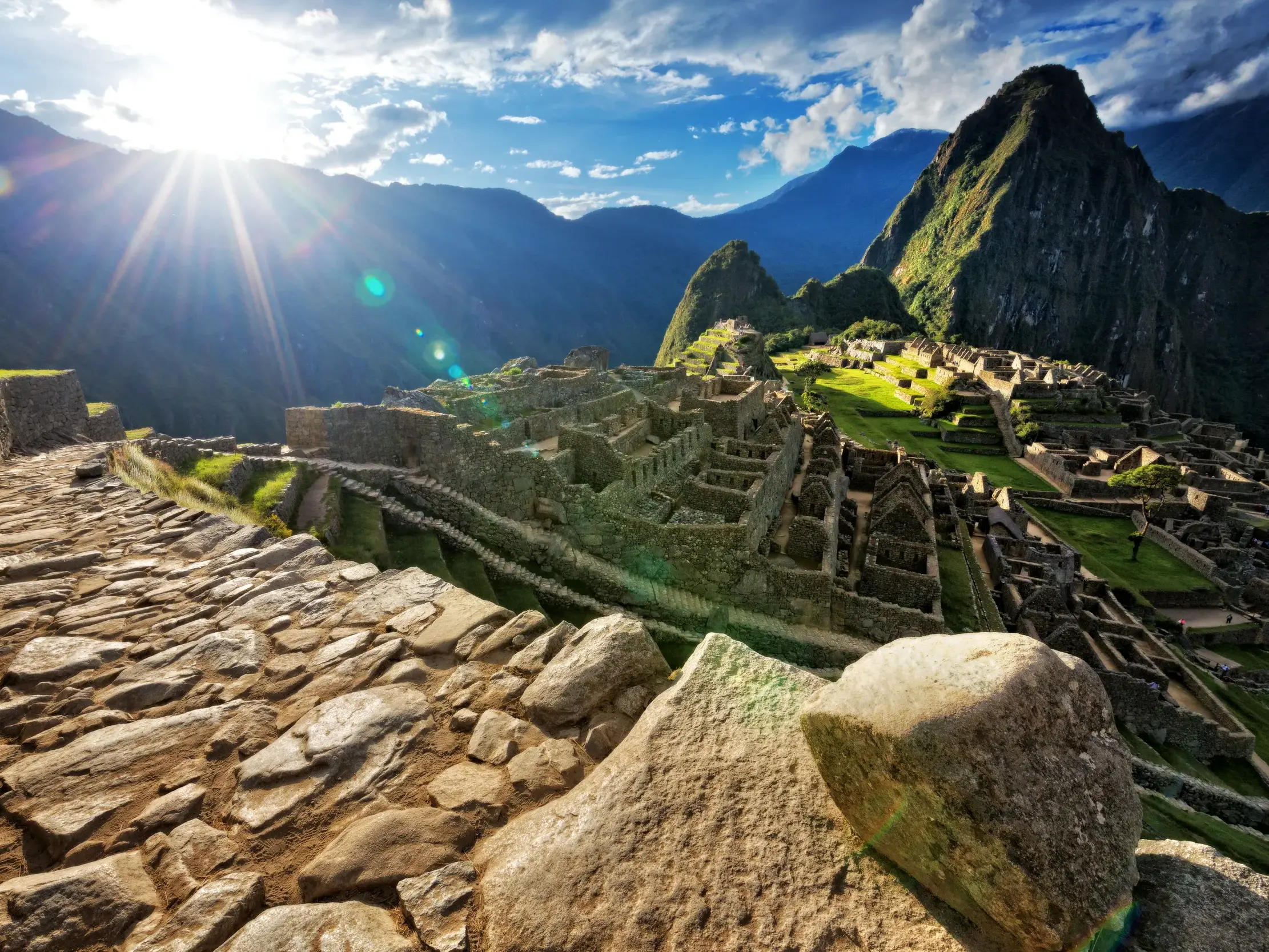 Sonniger Panoramablick von einem alten Inka-Pfad auf die berühmte Ruinenstadt Machu Picchu in den Anden von Peru.