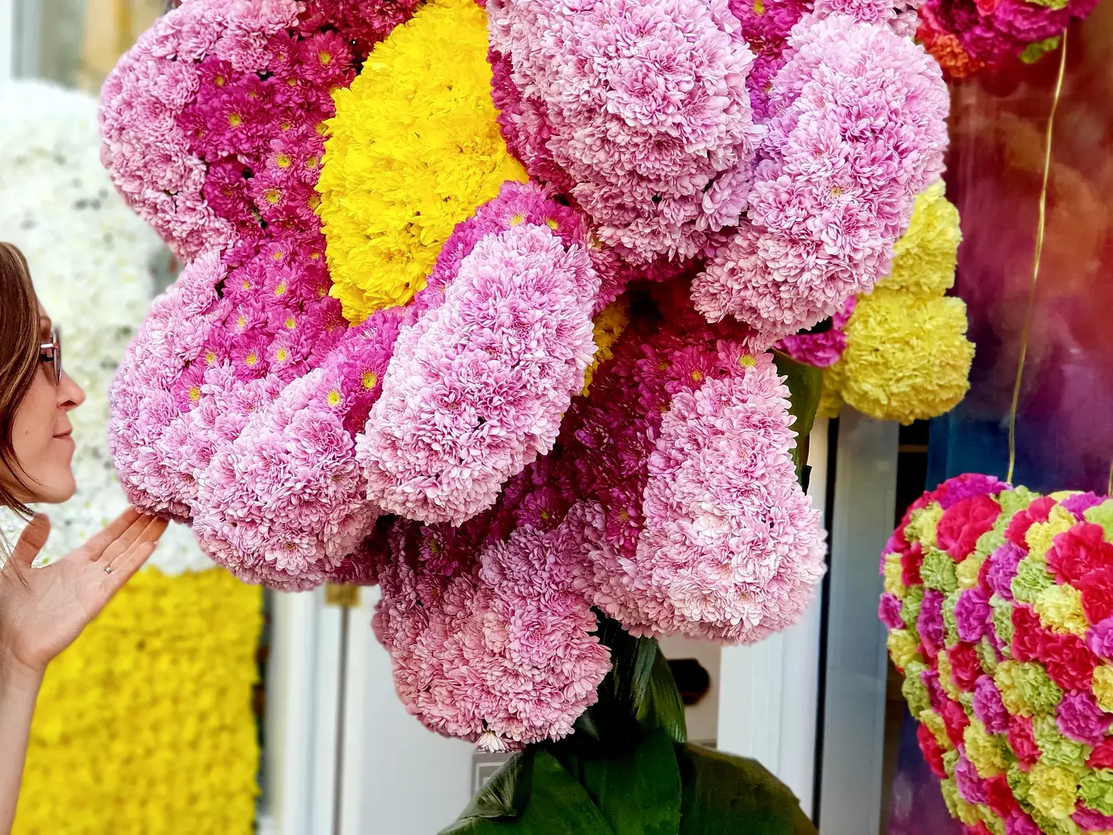 Frau bestaunt farbenfrohe Blütenskulpturen im Londoner Stadtviertel Chelsea.