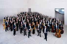 Die Wiener Symphoniker mit ihren Instrumenten in festlicher Abendgarderobe vor einem Konzertauftritt.