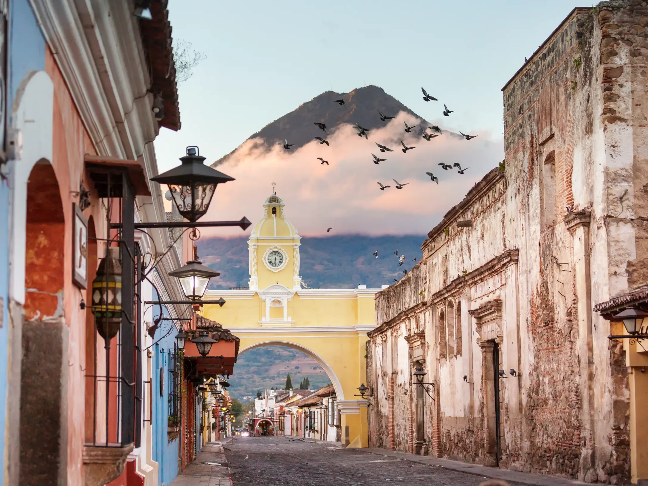 Der gelbe Uhrenbogen Arco de Santa Catalina in der Kolonialstadt Antigua mit Blick auf den majestätischen Vulkan de Agua.