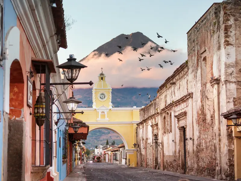 Der gelbe Uhrenbogen Arco de Santa Catalina in der Kolonialstadt Antigua mit Blick auf den majestätischen Vulkan de Agua.