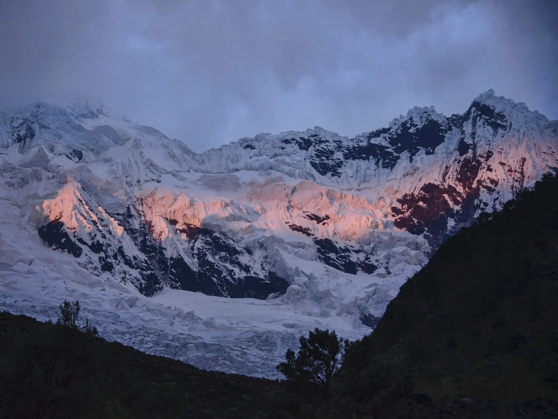 Die Abendsonne taucht die vergletscherten Gipfel der Cordillera Blanca in Peru während einer Trekkingreise in glutrotes Licht.