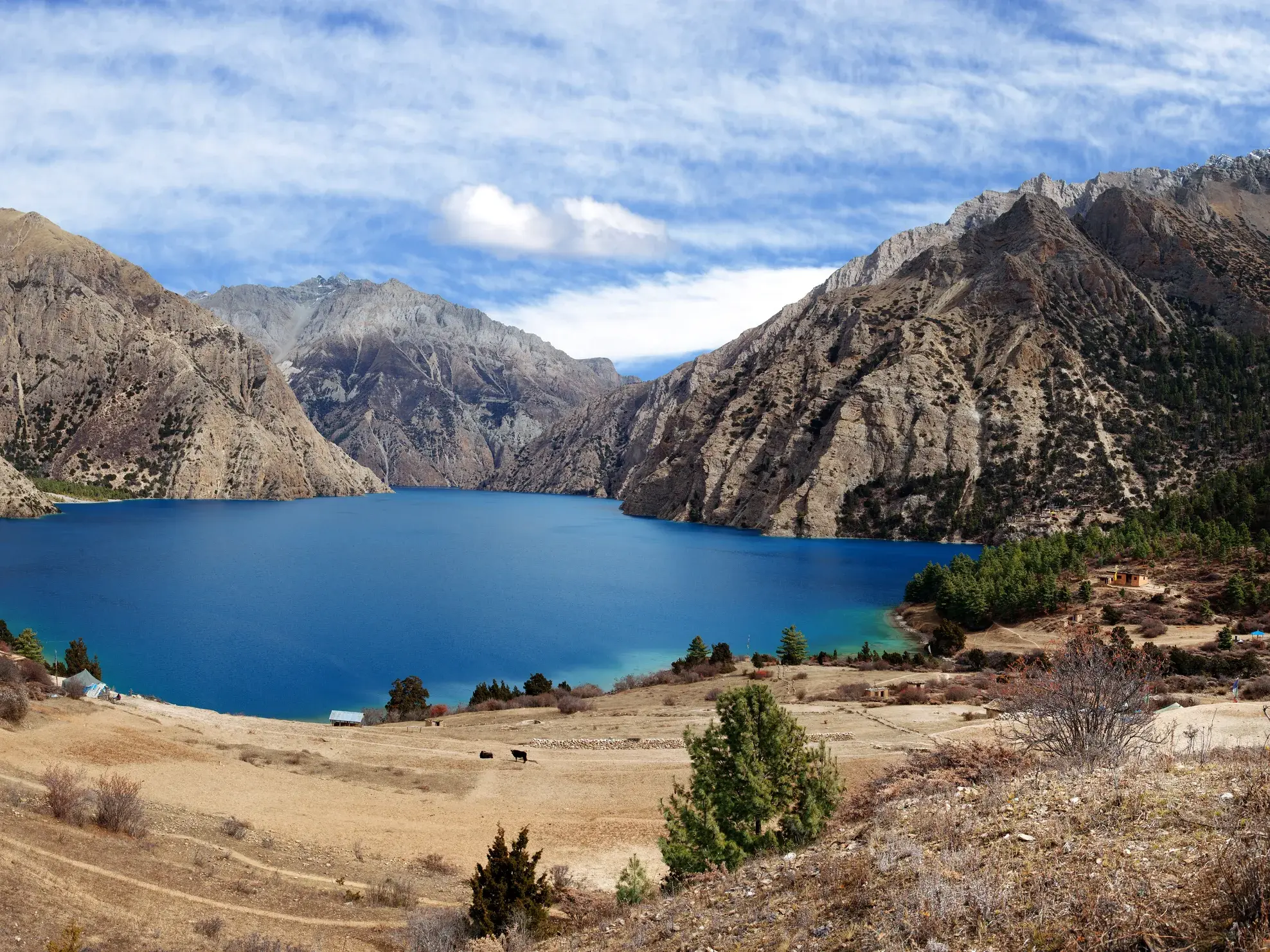 Atemberaubender Blick beim Trekking auf den azurblauen Phoksundo-See, umgeben von kargen Himalaya-Bergen im Dolpo, Nepal.