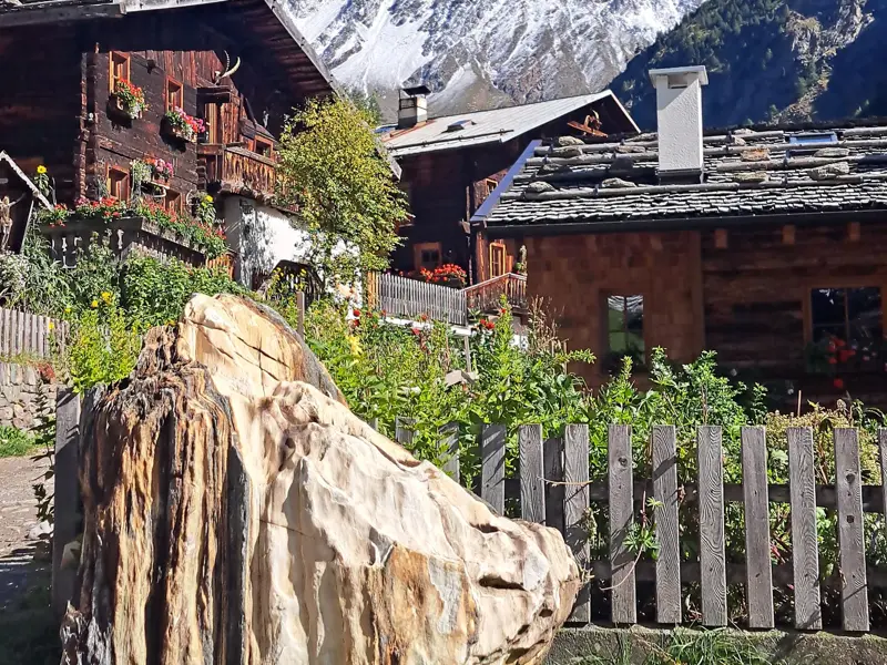 Traditionelle Bergbauernhöfe aus Holz mit Blumenschmuck und Steindächern im sonnigen Naturpark Texelgruppe in Südtirol.