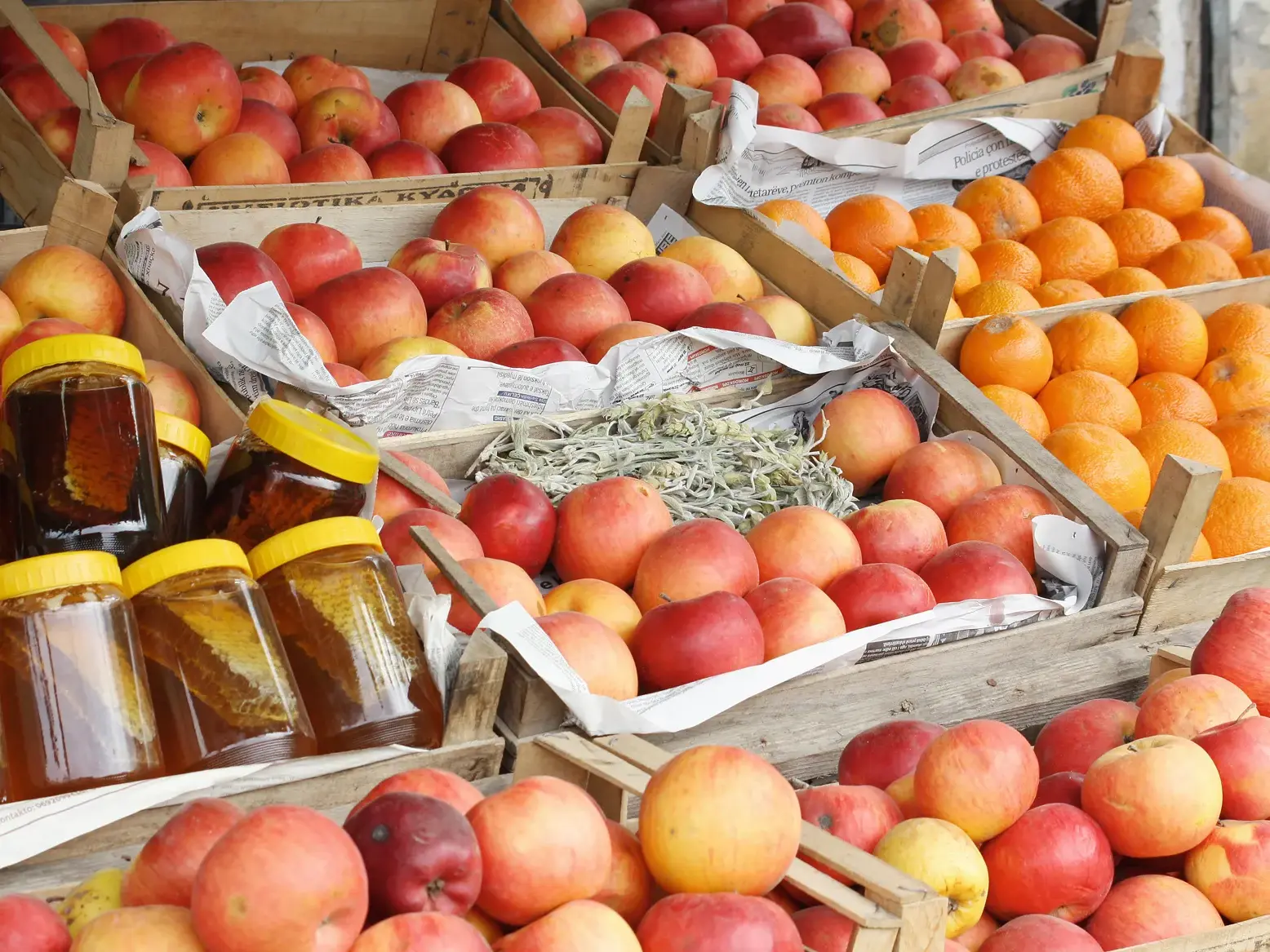 Frische Äpfel, Orangen und Gläser mit Honigwaben in Holzkisten auf dem Bauernmarkt von Ohrid in Nordmazedonien.